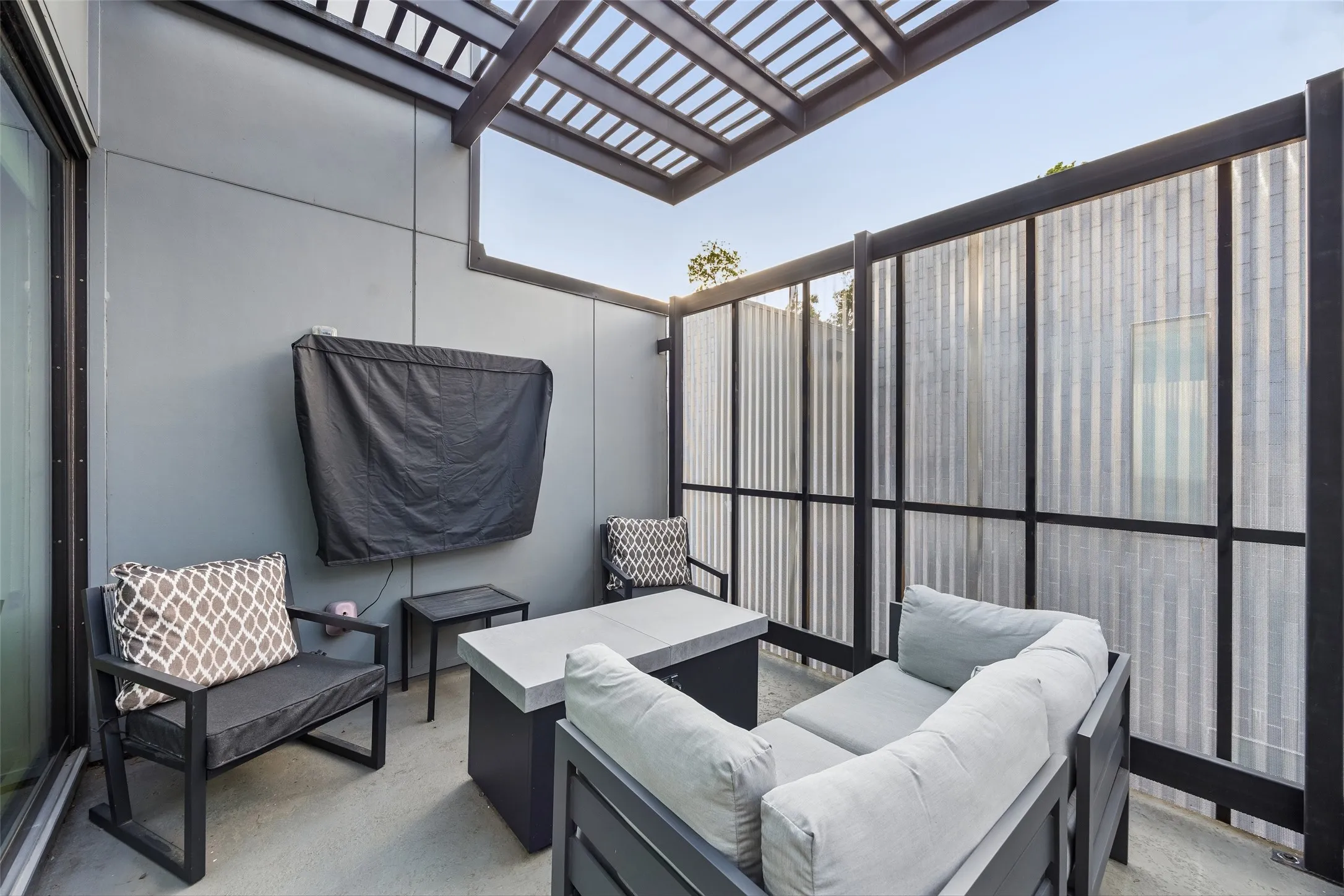 Outdoor patio featuring a slatted pergola, privacy screen, and a concrete floor