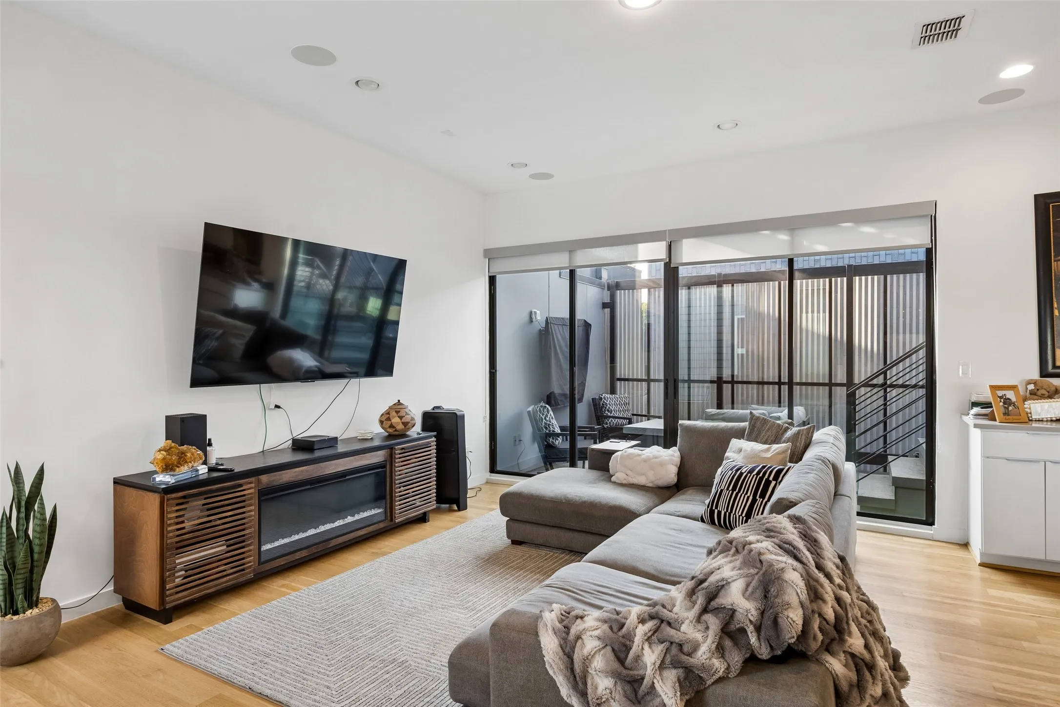 Living area featuring hardwood floors, high ceilings with recessed lighting, and large sliding glass doors providing access to an outdoor area