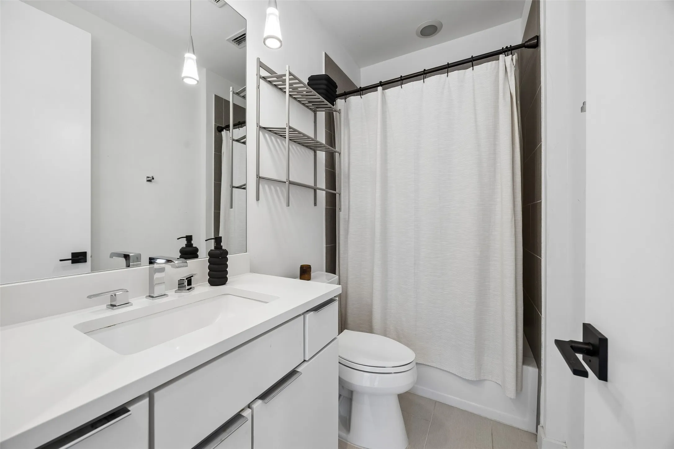Bathroom featuring a white vanity with an integrated sink, chrome fixtures, and a large mirror