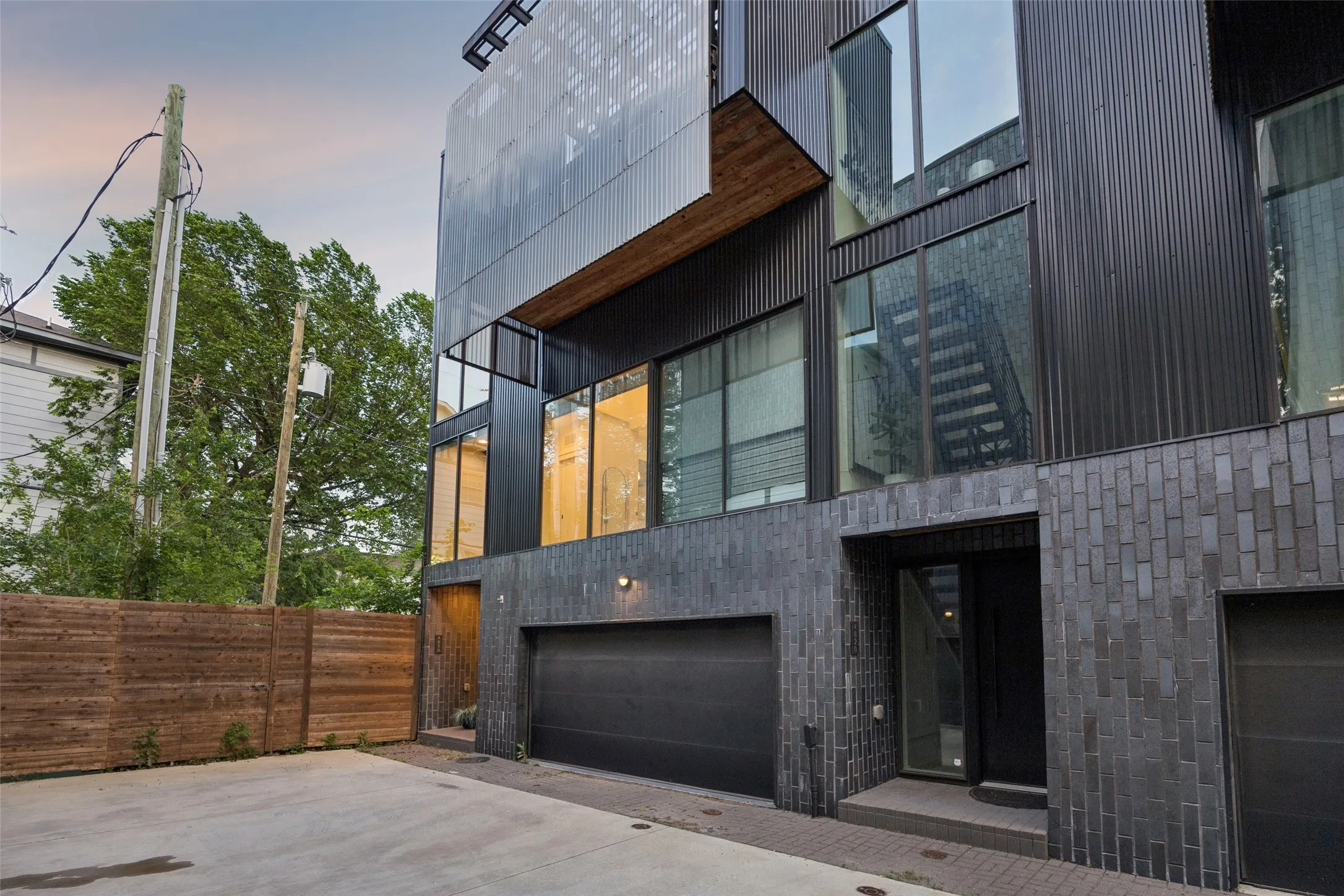 The property features a contemporary exterior with dark corrugated metal siding, large windows, and a dark brick facade
