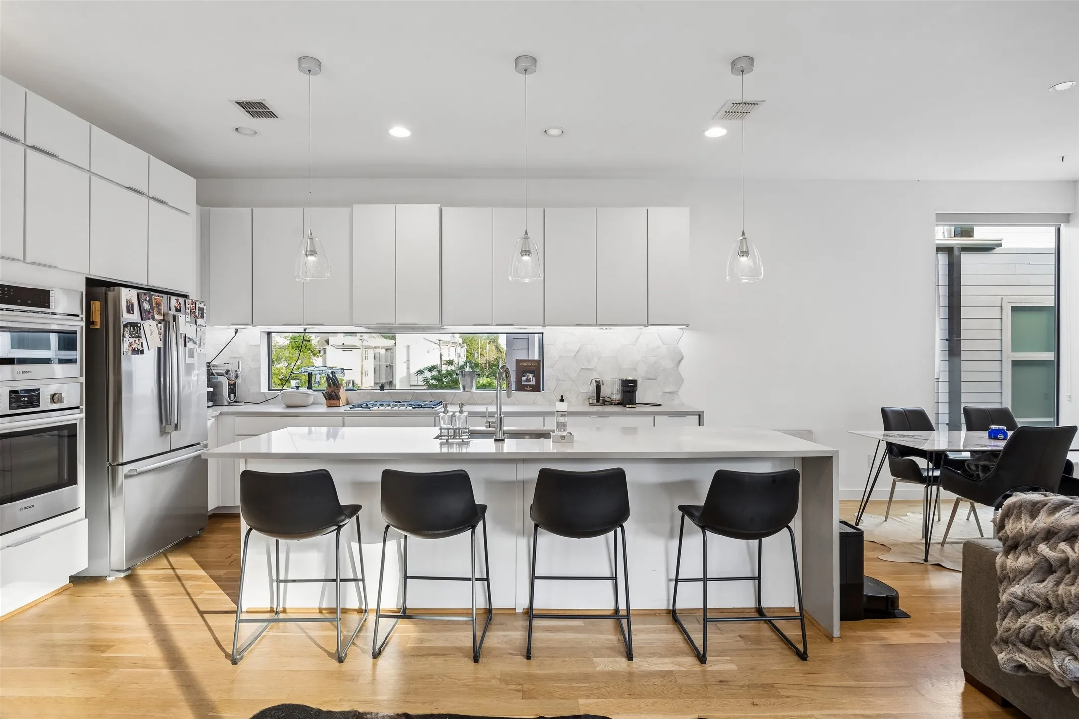 Contemporary kitchen featuring white cabinetry, a large kitchen island with seating, stainless steel appliances, and hardwood floors
