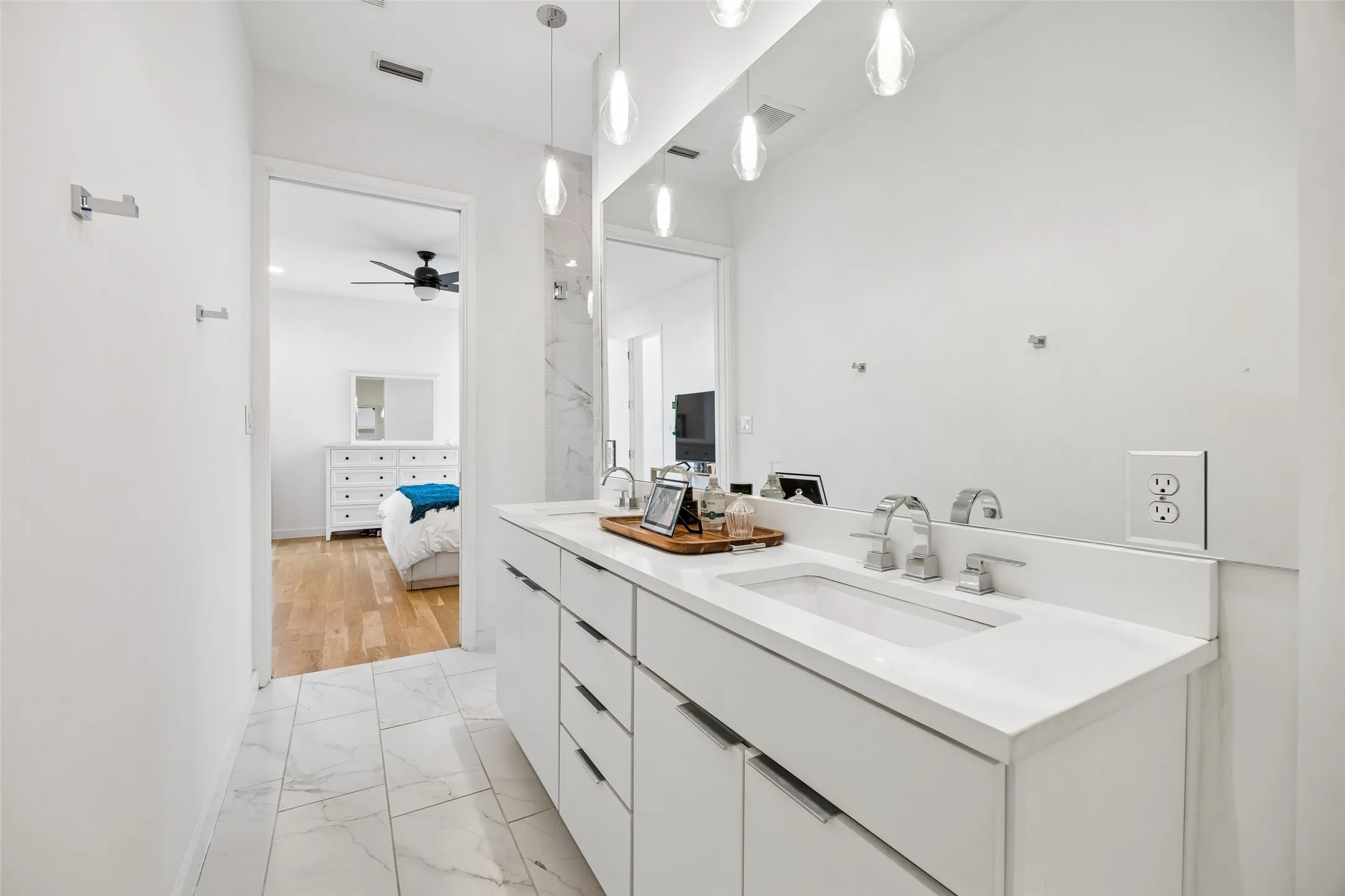 Bathroom featuring a double vanity with white countertops, modern chrome fixtures, and a large mirror