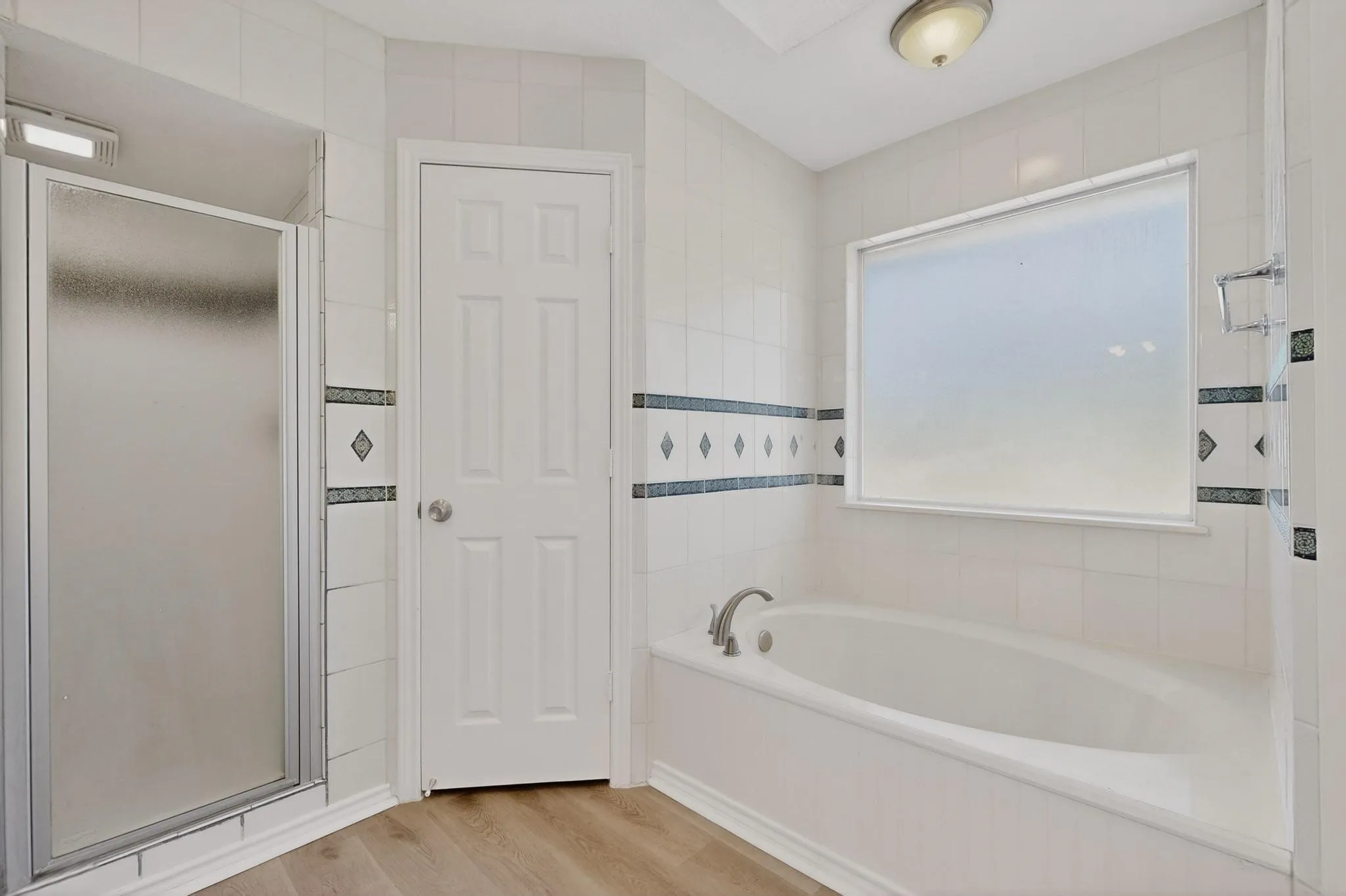 Full bathroom with a bath, a stall shower, light wood finished floors, and tile walls