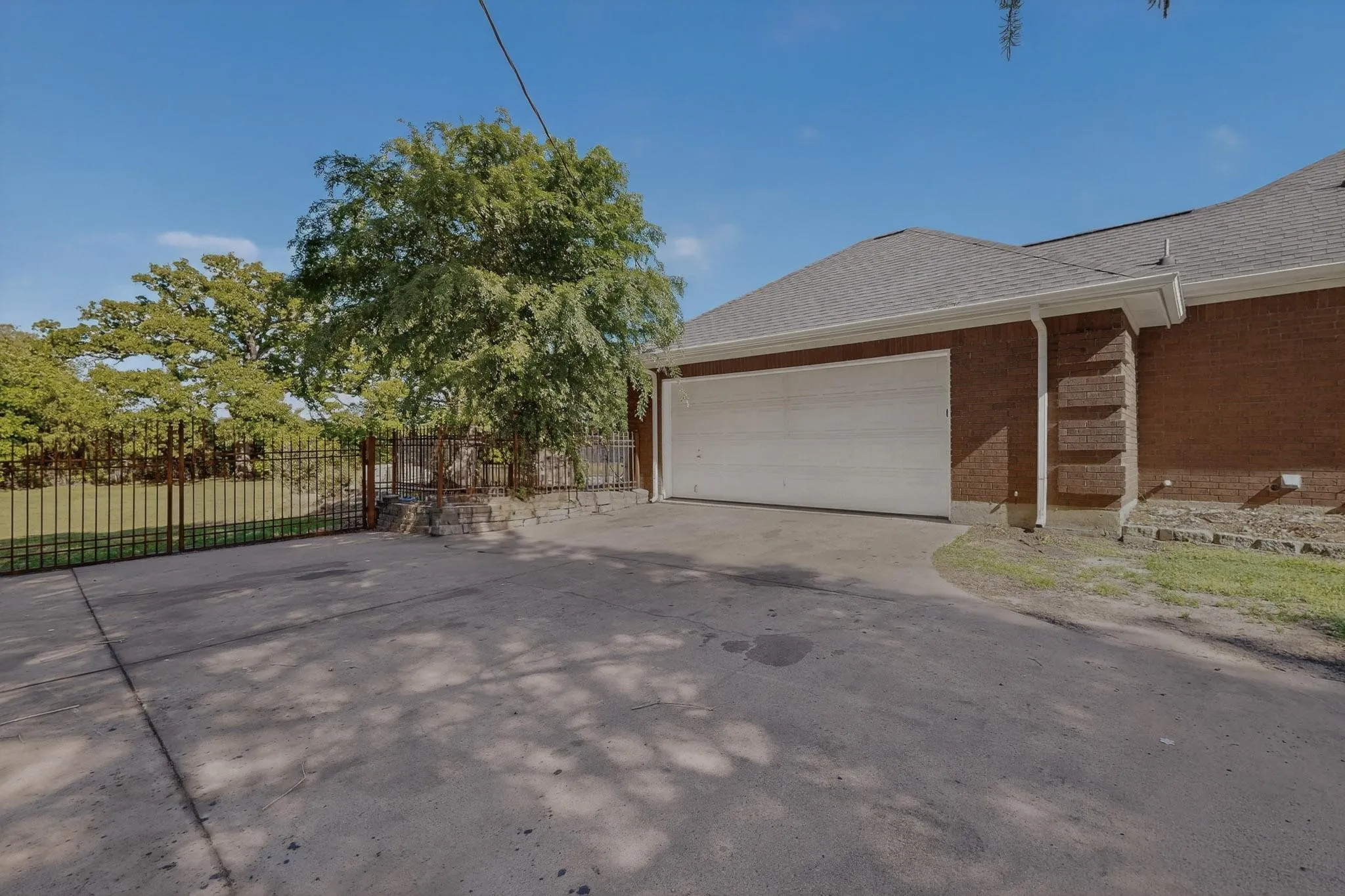 View of side of home featuring roof with shingles, concrete driveway, an attached garage, and brick siding
