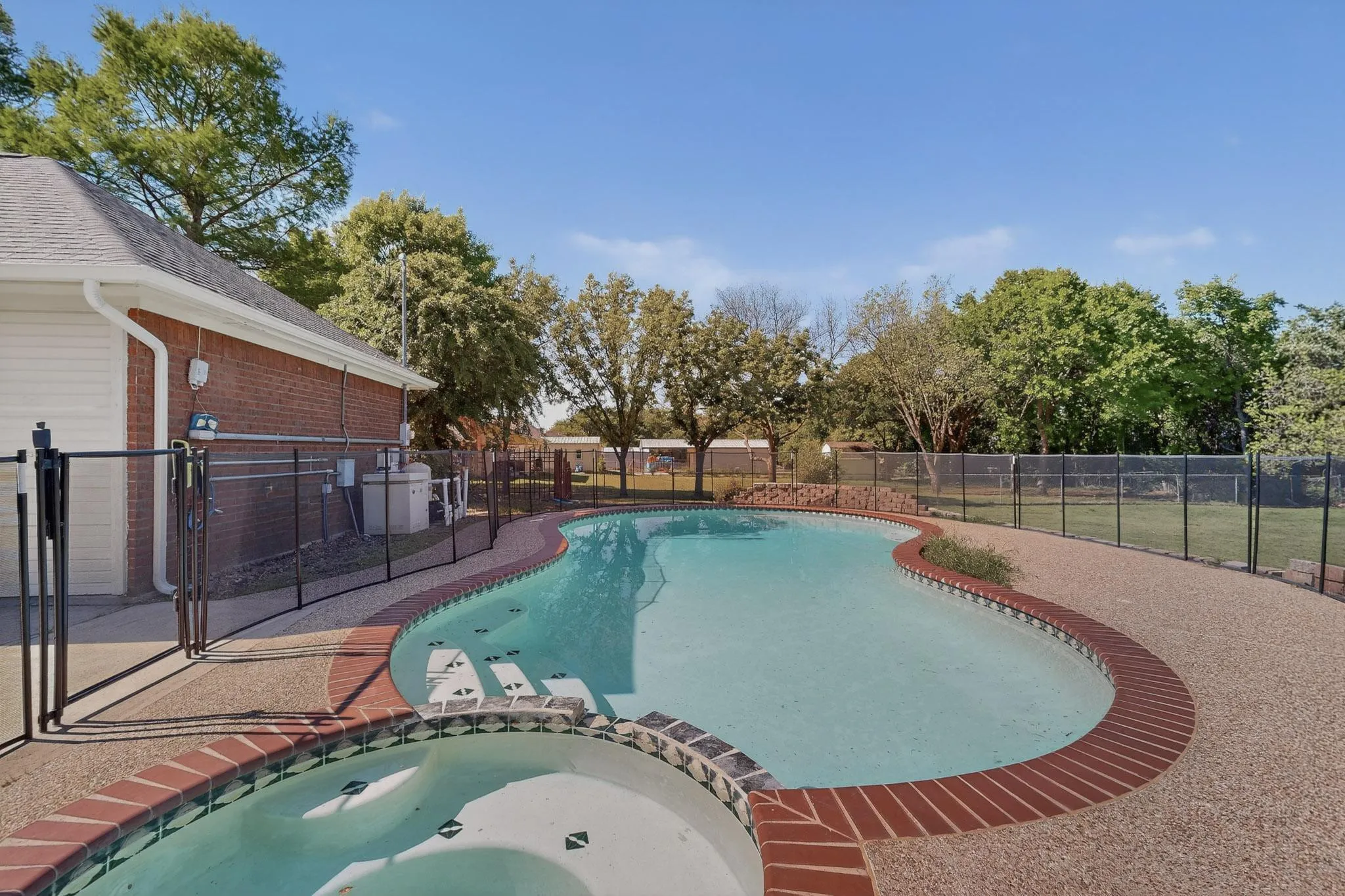 Integrated pool / hot tub with a fenced backyard and a patio