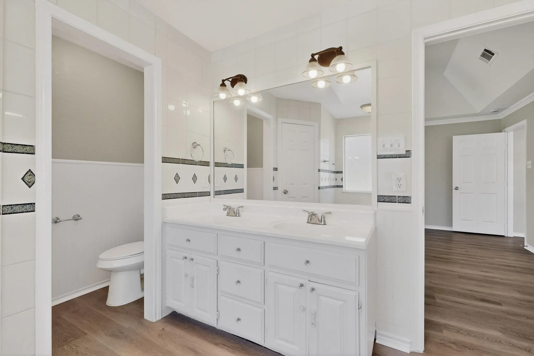 Bathroom featuring double vanity, light wood-type flooring, and tile walls