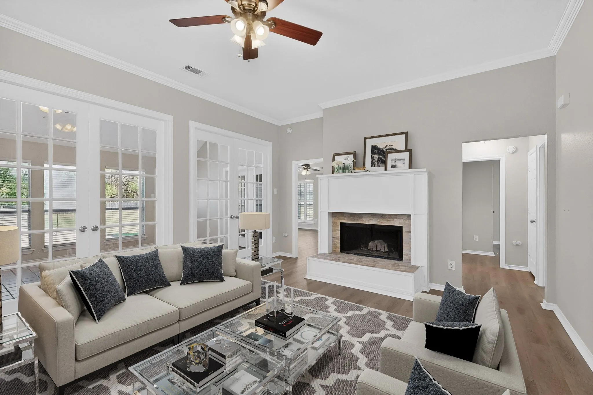 Living room featuring ceiling fan, french doors, wood finished floors, crown molding, and a fireplace with raised hearth