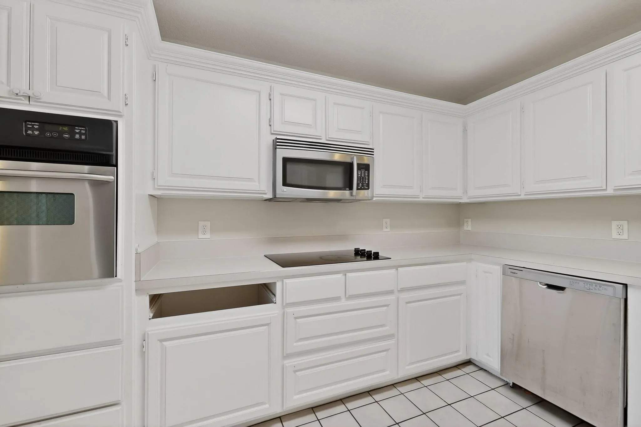 Kitchen featuring stainless steel appliances, light countertops, white cabinets, and light tile patterned floors