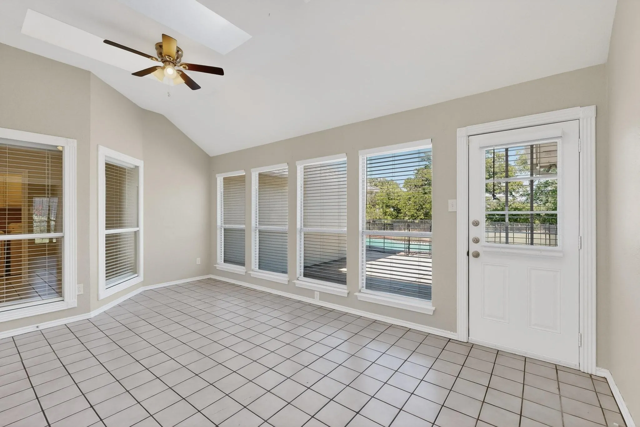 Unfurnished sunroom with a skylight, tile patterned flooring, and vaulted ceiling