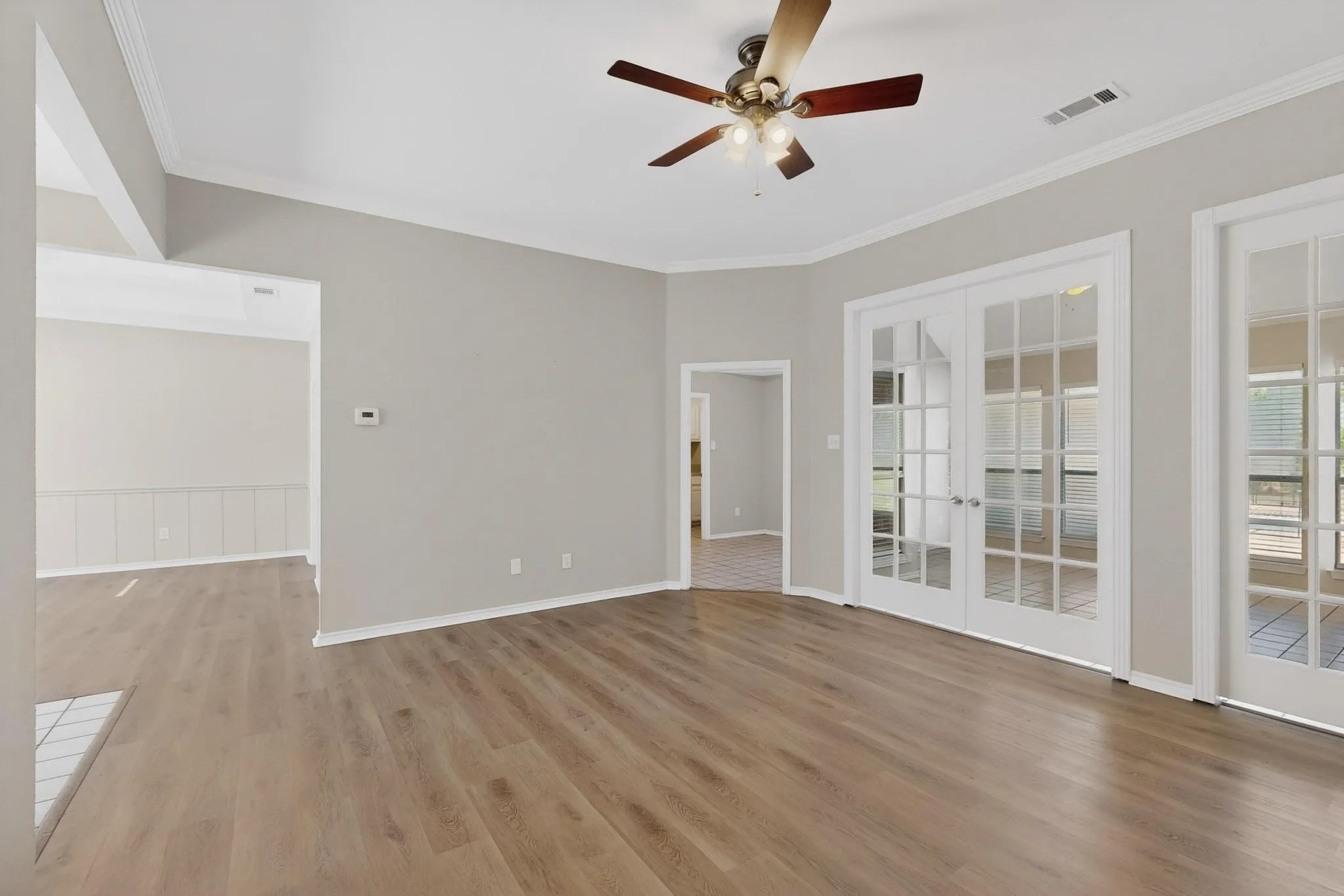 Unfurnished room featuring french doors, a ceiling fan, light wood finished floors, and crown molding