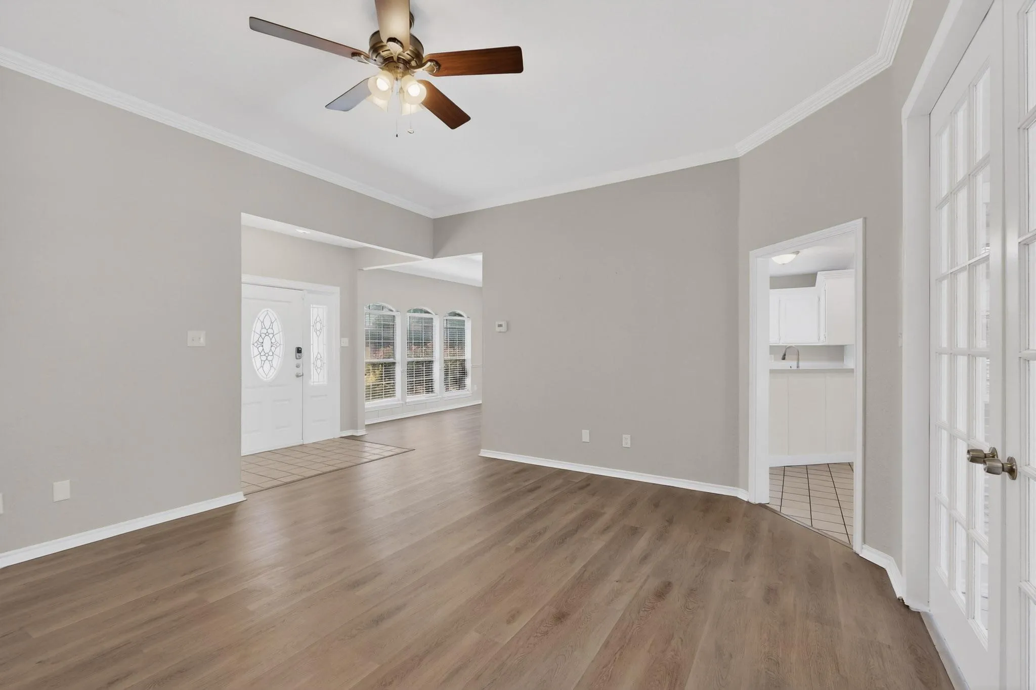 Unfurnished living room featuring a ceiling fan, ornamental molding, and dark wood-type flooring