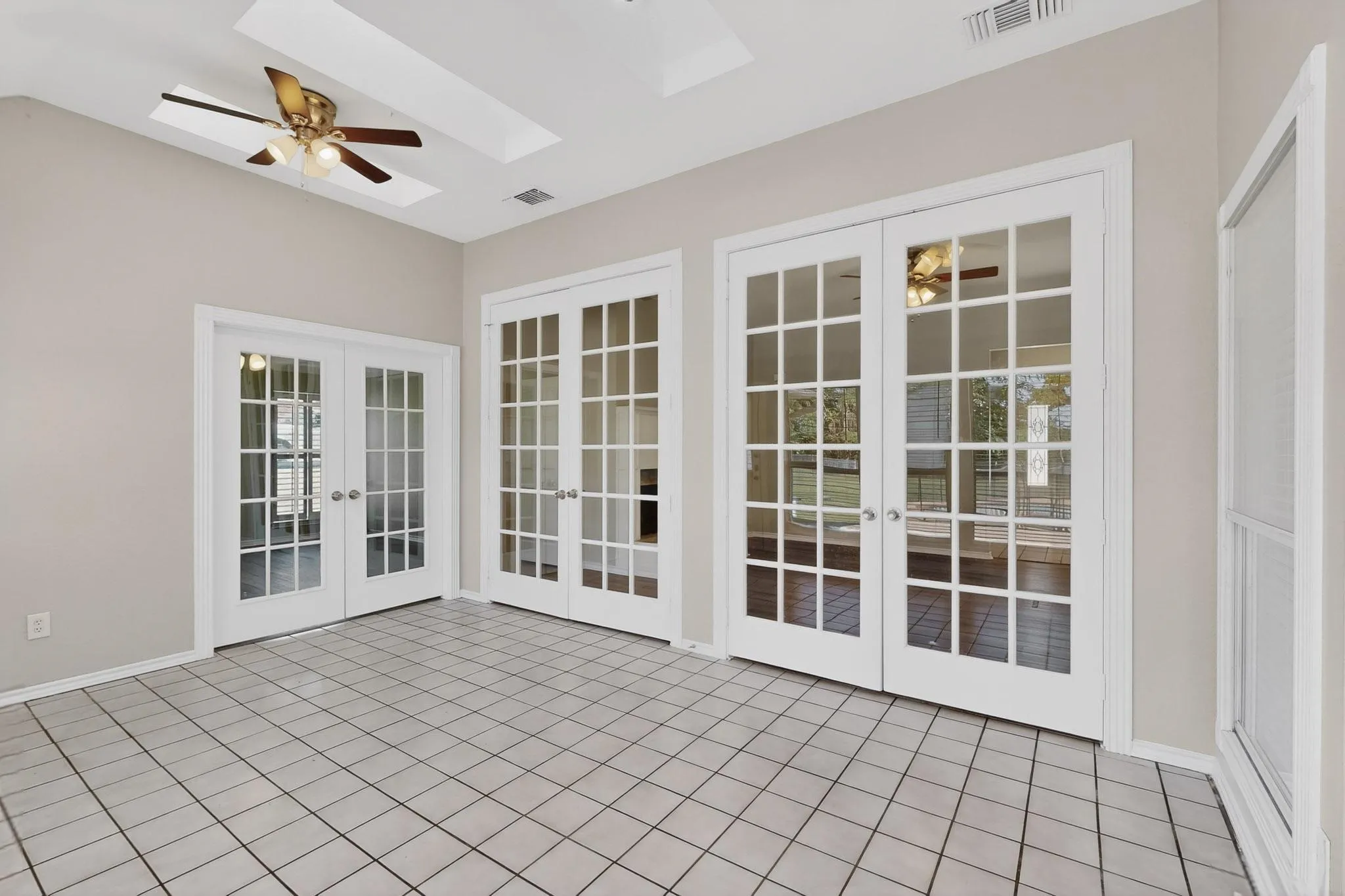 Unfurnished sunroom with french doors, a skylight, and tile patterned flooring