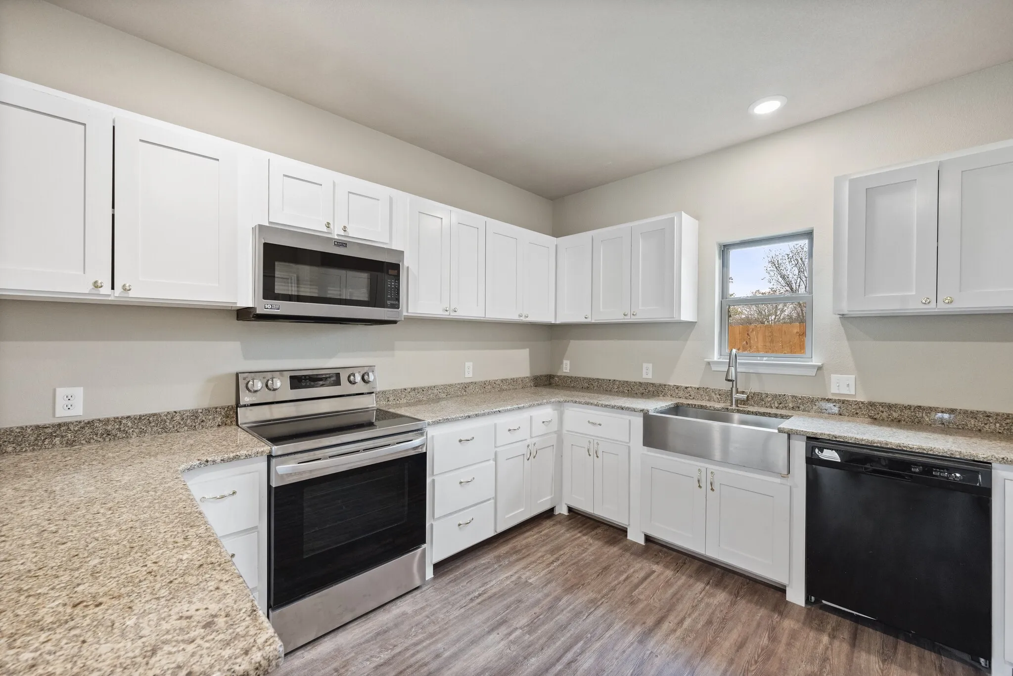 Kitchen featuring stainless steel appliances, light stone countertops, and white cabinets