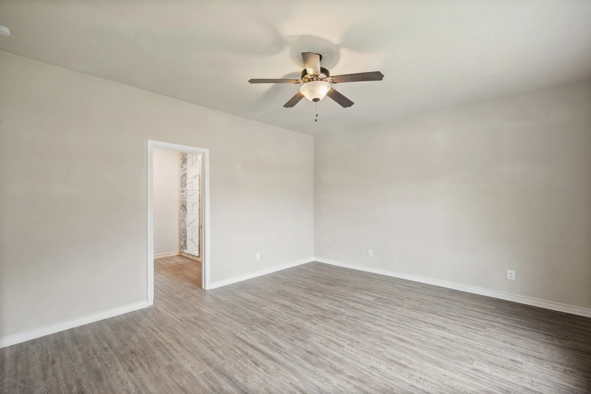 Empty room with a ceiling fan and light wood-style floors