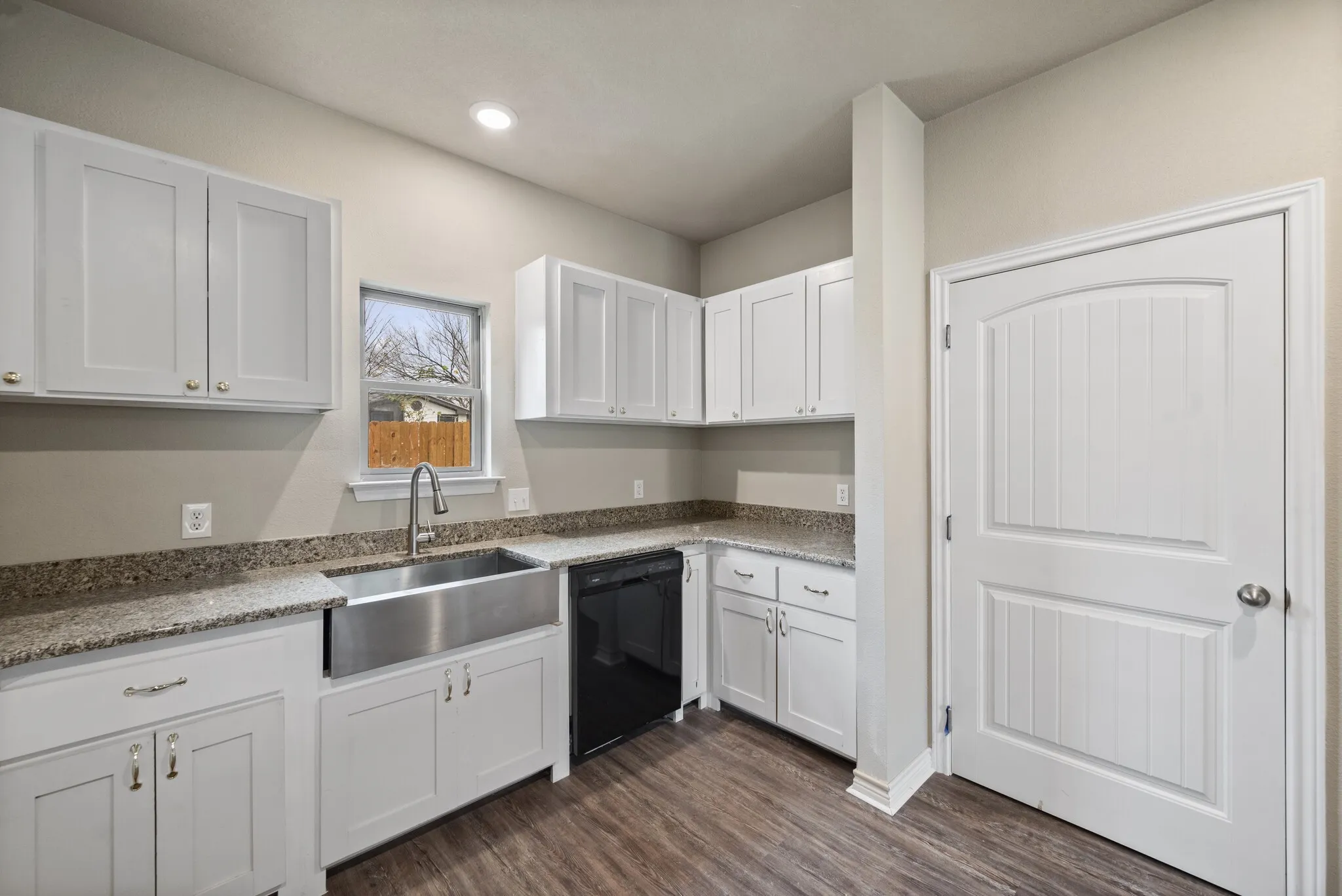 Kitchen with white cabinetry, light stone counters, dishwasher, and dark wood-style floors