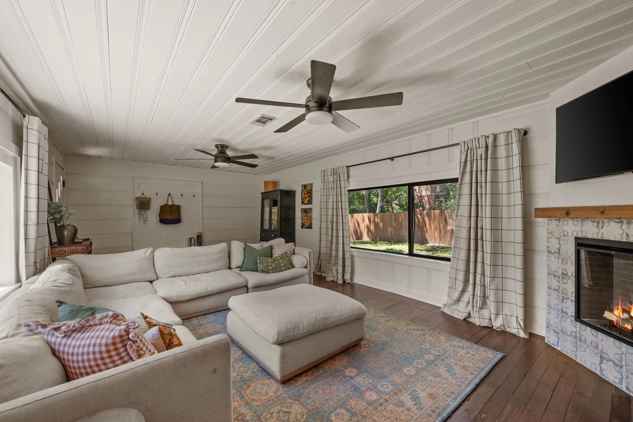 Living room featuring wood-type flooring, a ceiling fan, a fireplace, wood ceiling, and crown molding