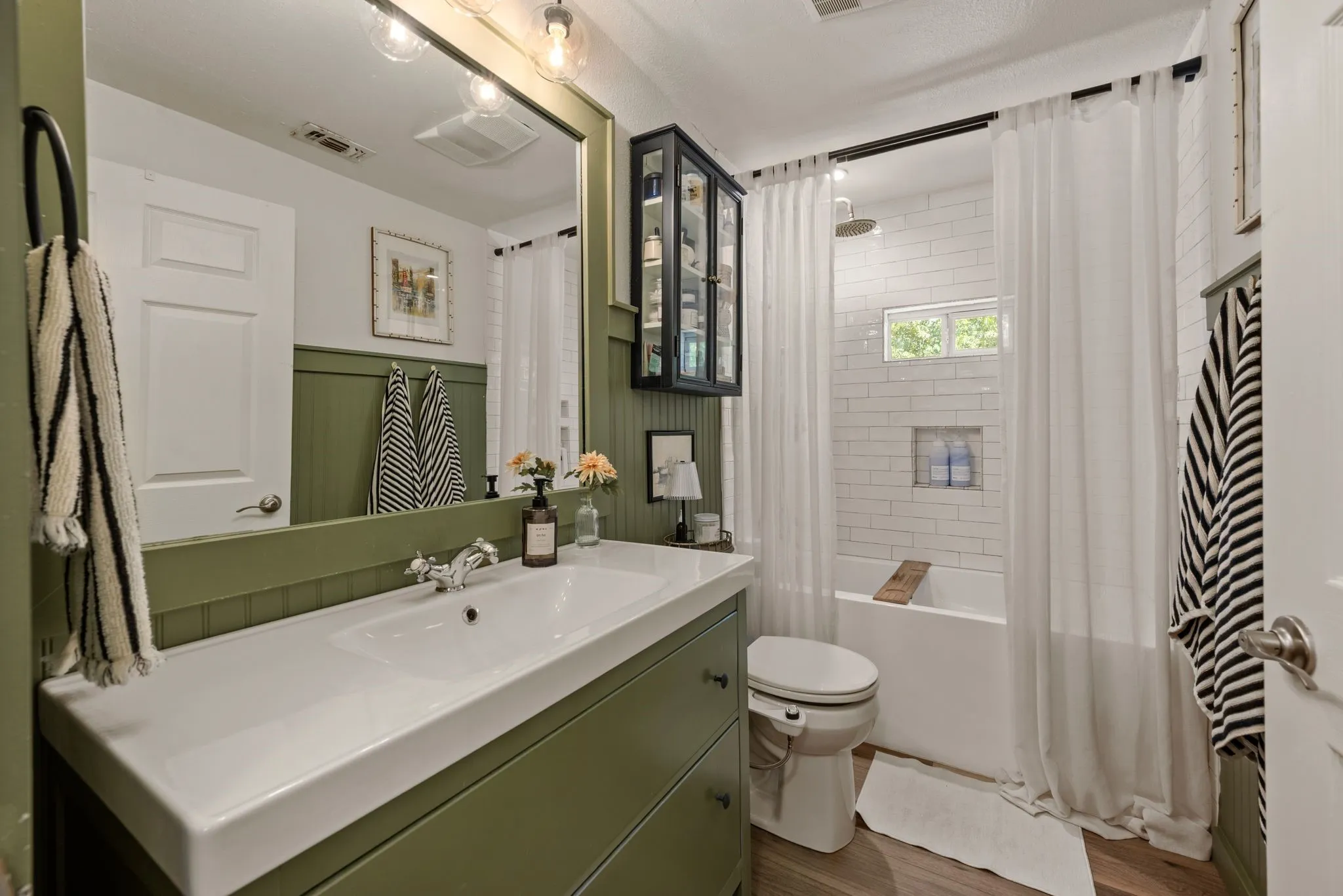 Full bath featuring vanity, shower / bath combo, and wood finished floors