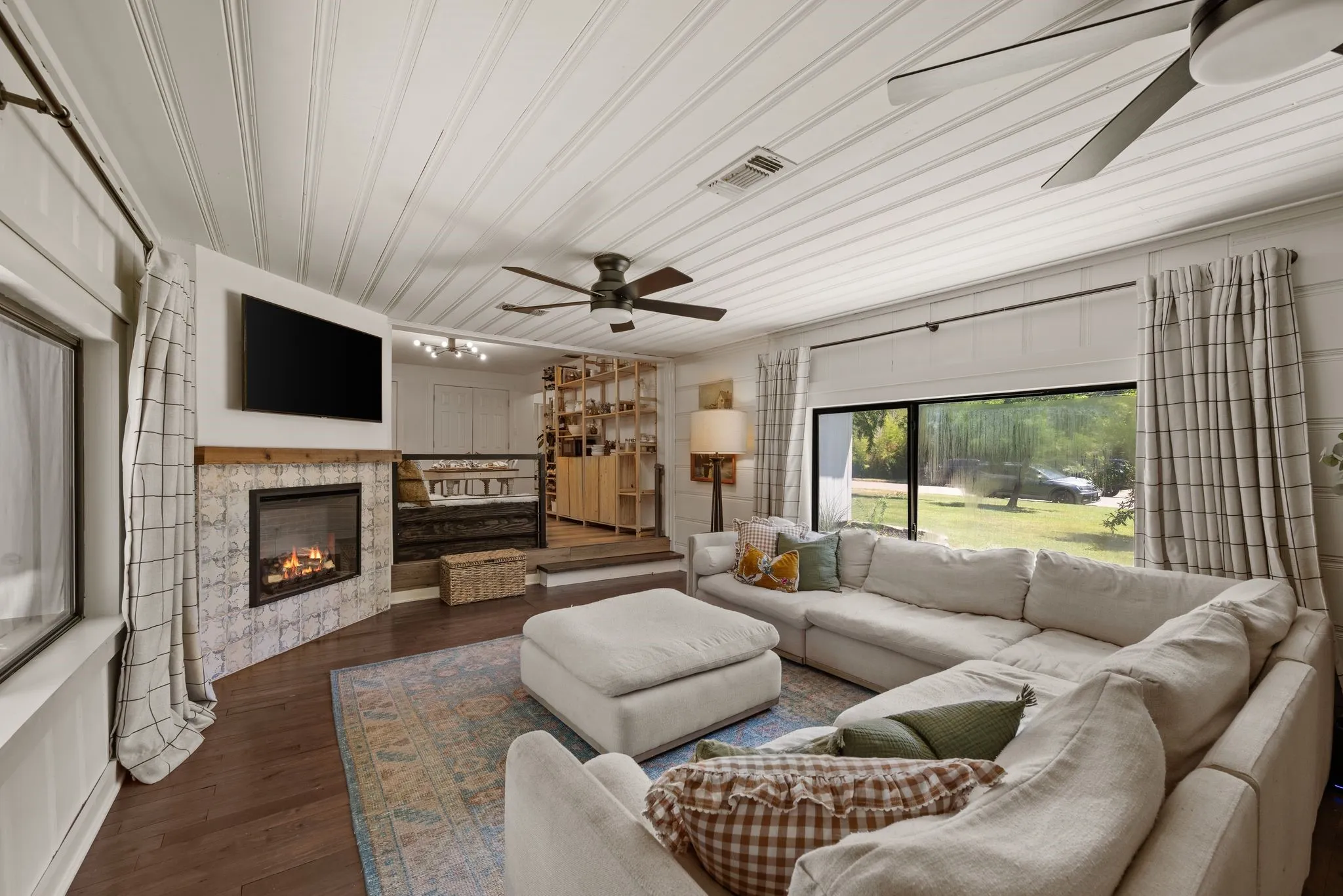 Living area featuring a glass covered fireplace, hardwood / wood-style floors, ceiling fan, and wooden ceiling