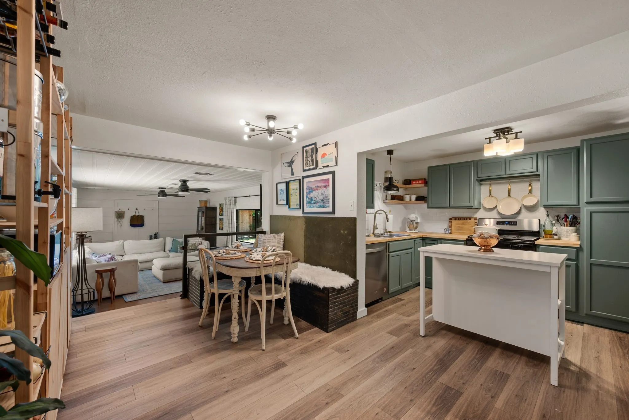 Kitchen featuring green cabinets, light countertops, light wood-style floors, a chandelier, and open shelves
