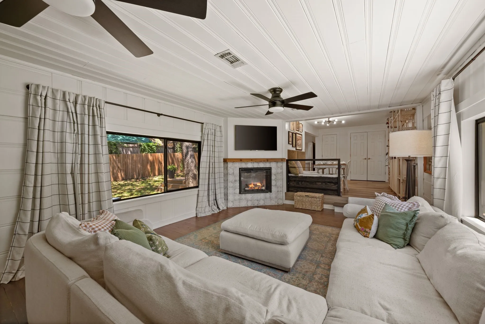 Living area featuring a tile fireplace, wood finished floors, a ceiling fan, and crown molding