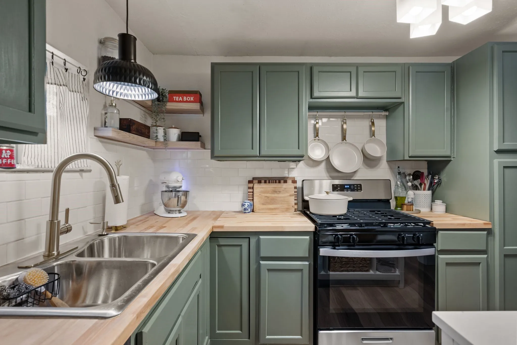Kitchen with green cabinetry and wood counters