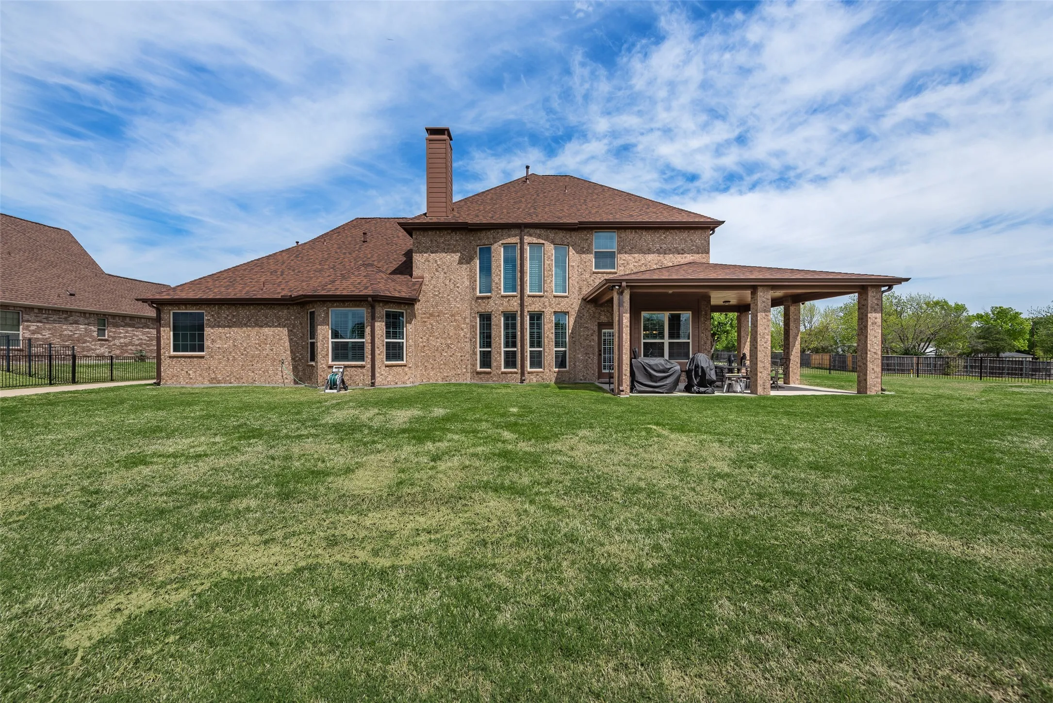 Back of property with a fenced backyard, a patio area, a chimney, brick siding, and a shingled roof