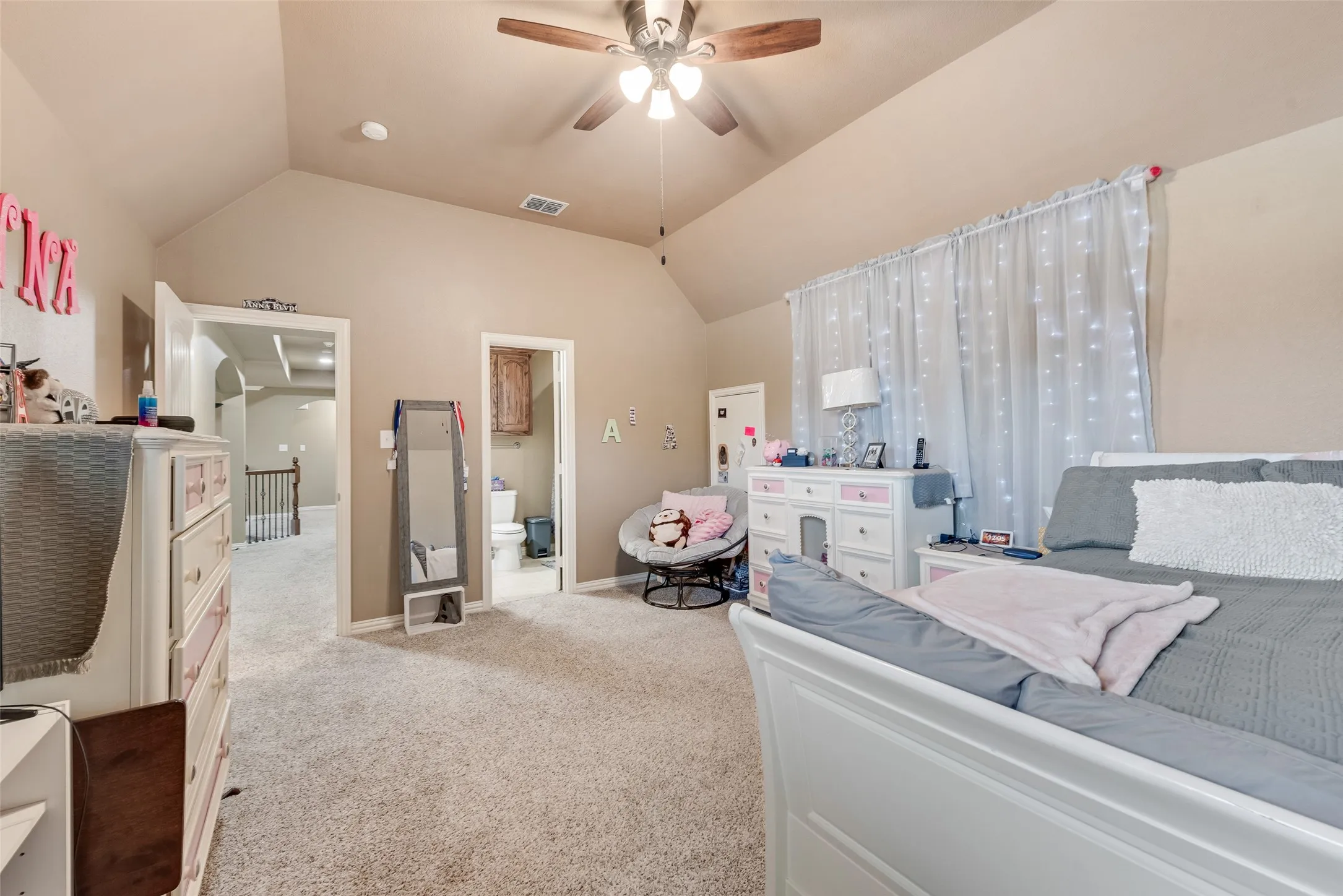 Bedroom with light carpet, a ceiling fan, and ensuite bathroom