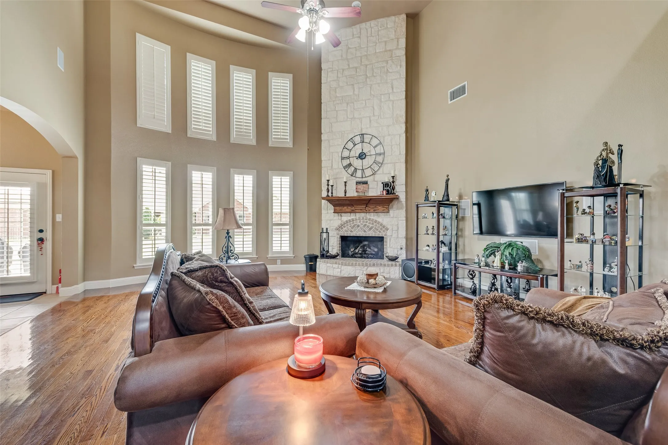 Living area with a fireplace, light wood-type flooring, a high ceiling, arched walkways, and plenty of natural light