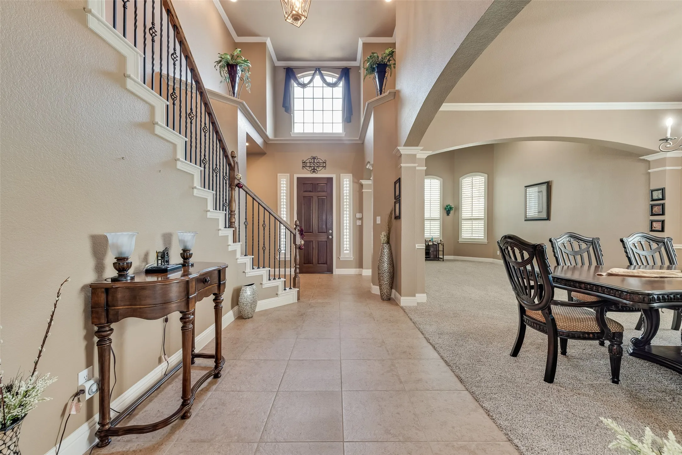 Foyer with a high ceiling, arched walkways, crown molding, light tile patterned floors, and light carpet