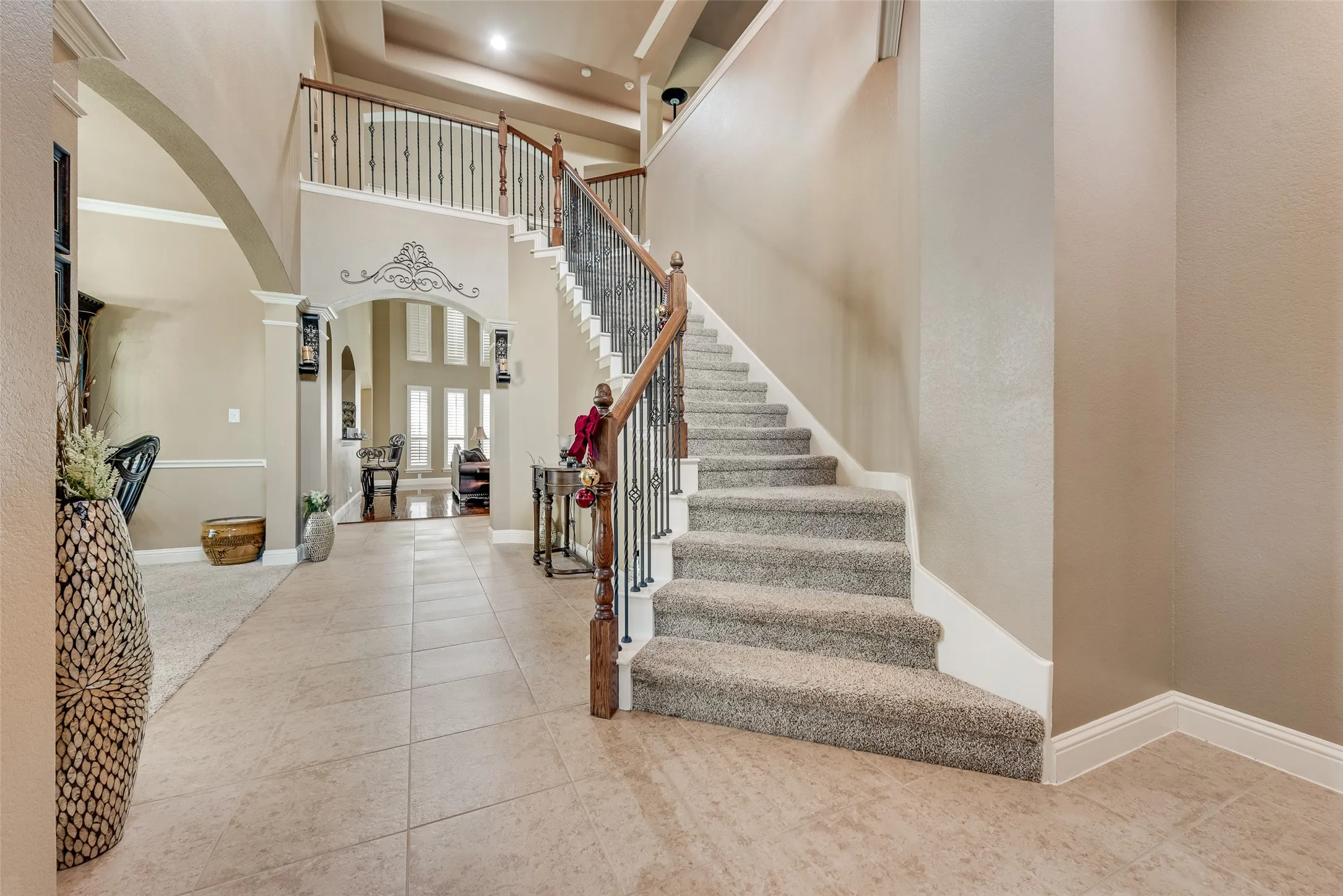 Foyer entrance with arched walkways, a high ceiling, light tile patterned floors, and decorative columns