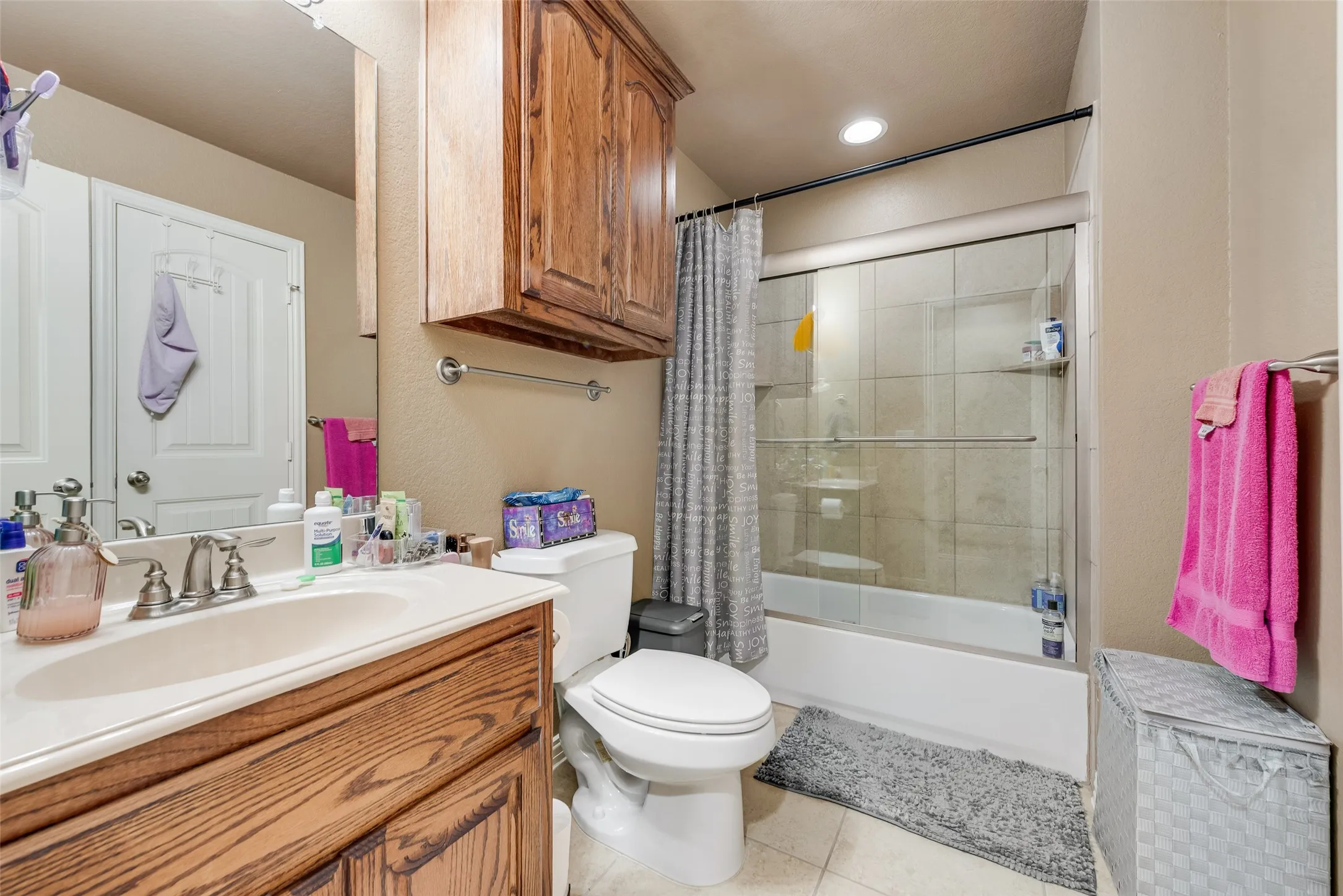 Bathroom featuring shower / bath combination with glass door, vanity, light tile patterned floors, and recessed lighting