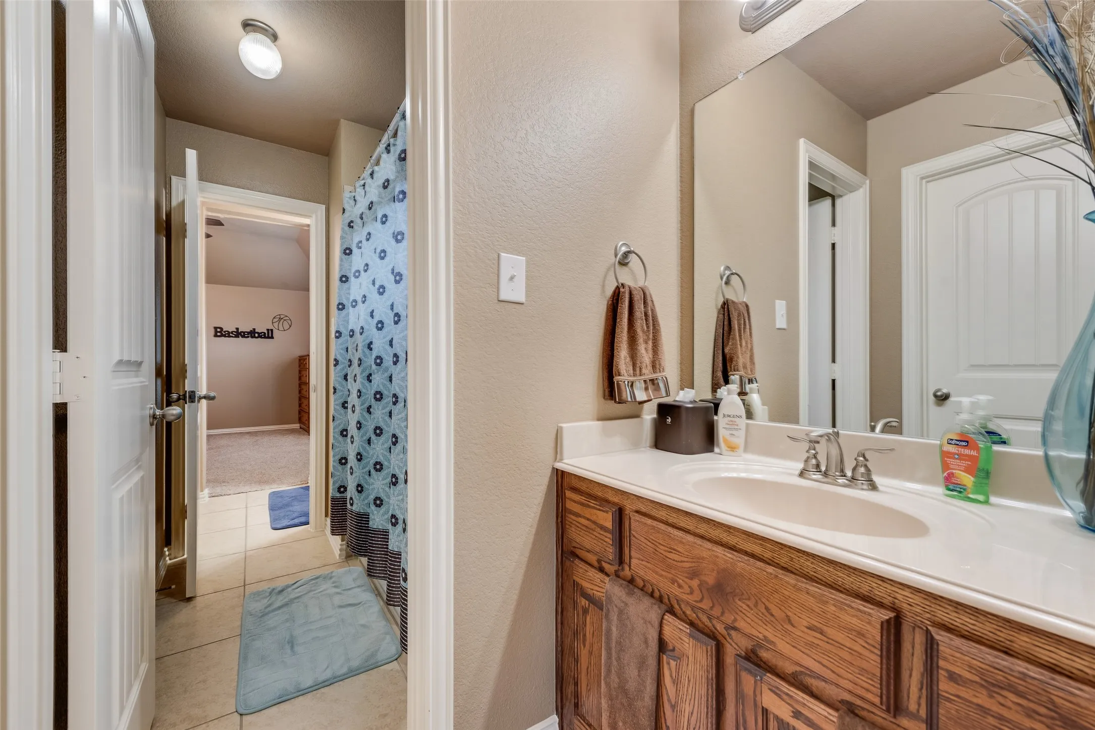 Full bathroom with vanity, curtained shower, and light tile patterned floors