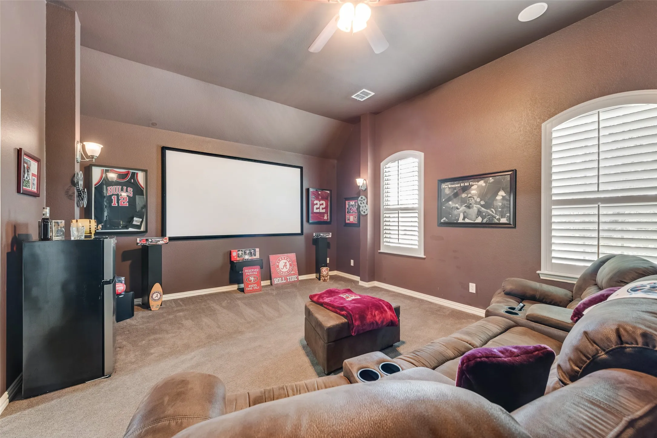 Home theater featuring a ceiling fan, carpet floors, and vaulted ceiling