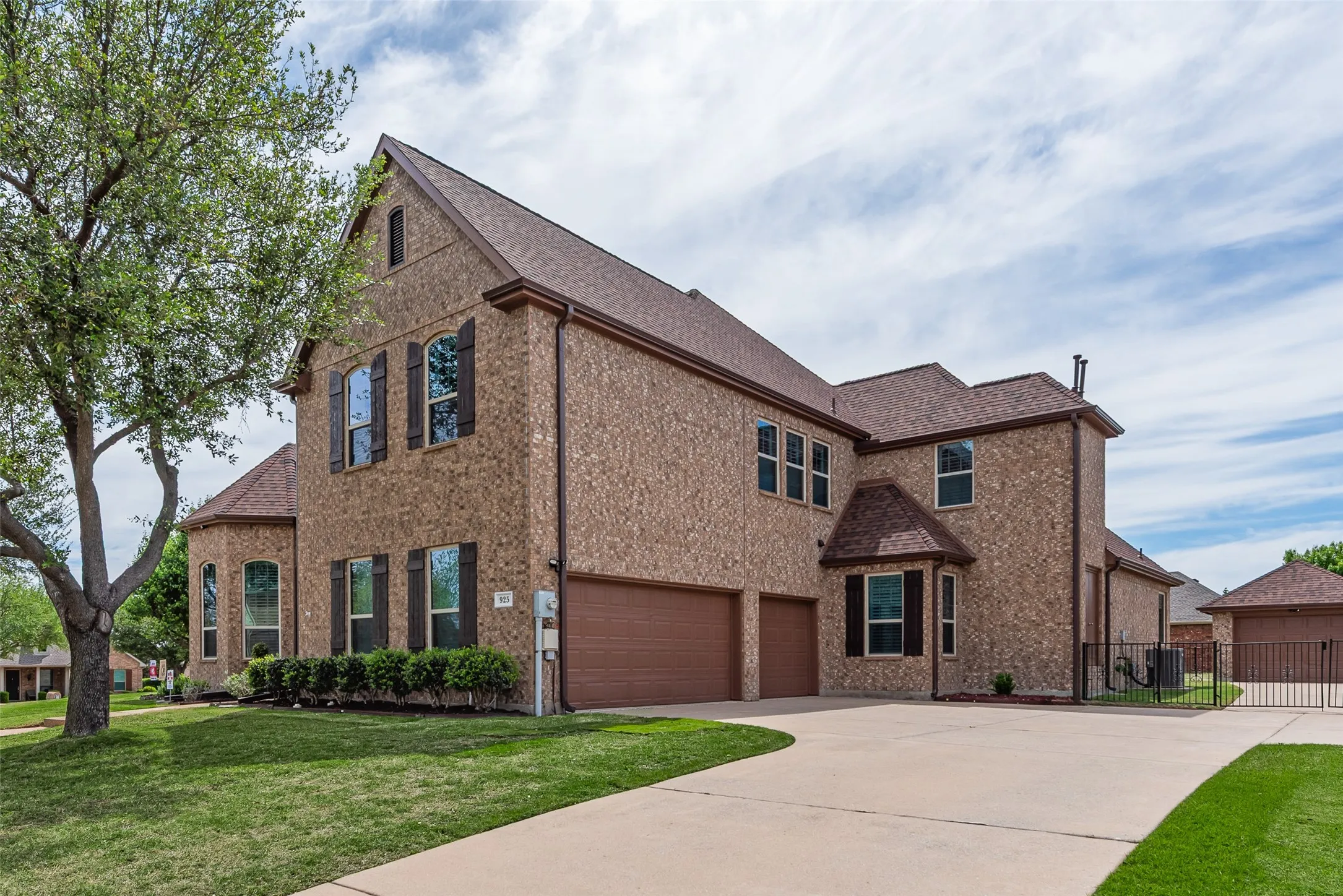 View of front of home with a shingled roof, an attached garage, brick siding, a front lawn, and concrete driveway
