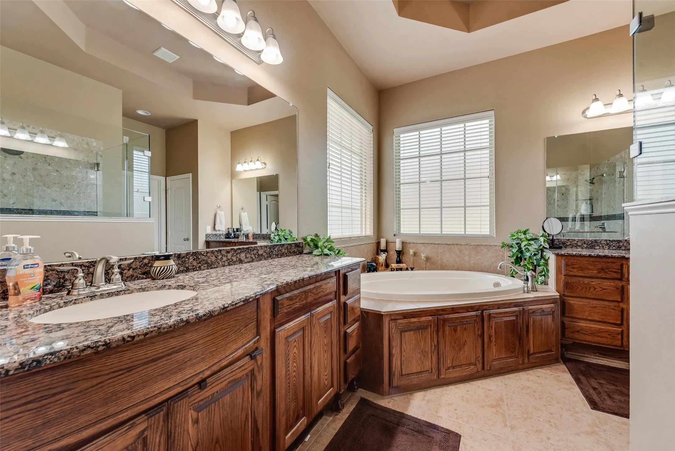 Full bath with vanity, a bath, walk in shower, light tile patterned flooring, and a raised ceiling