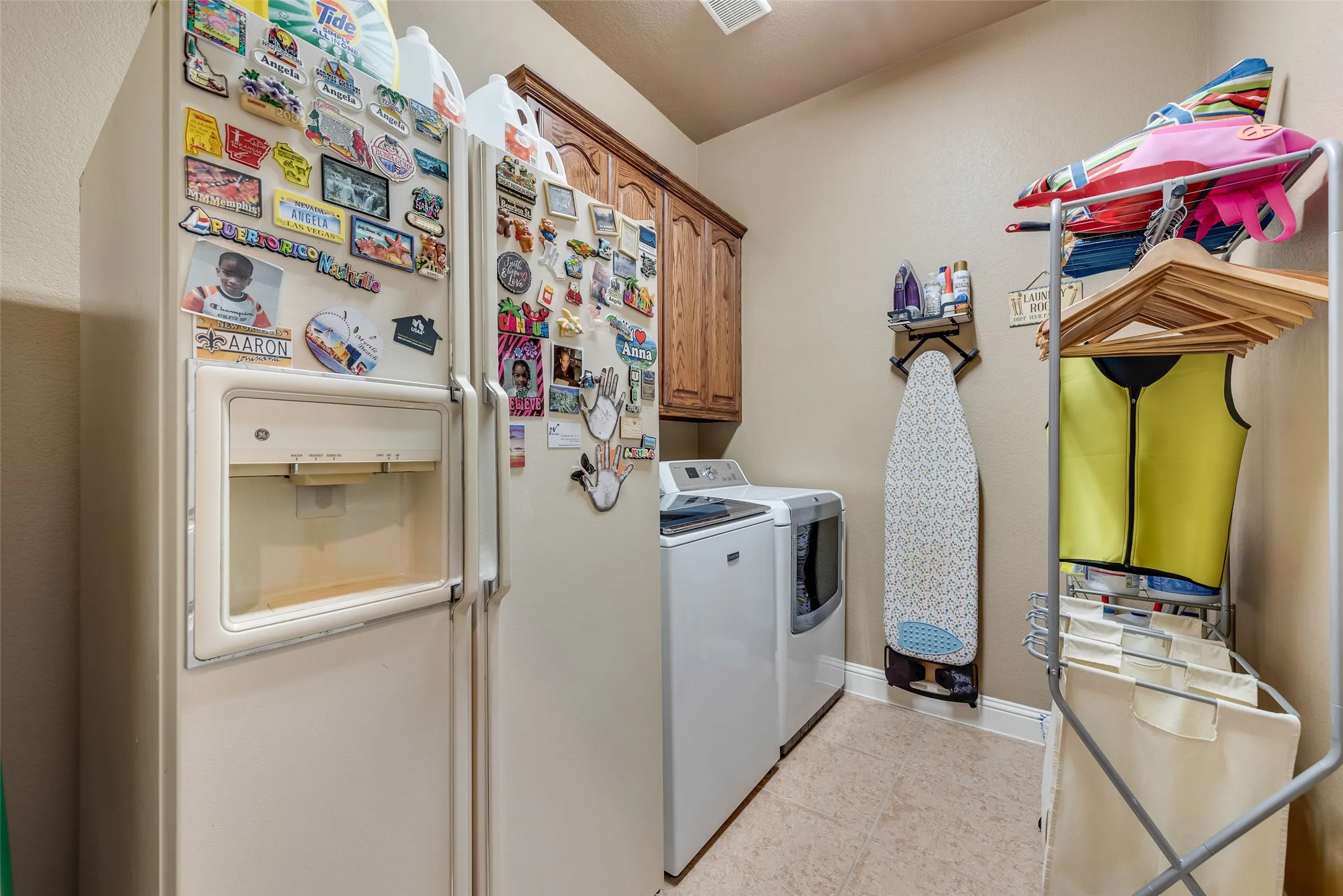 Laundry area with cabinet space, washer and dryer, and light tile patterned floors