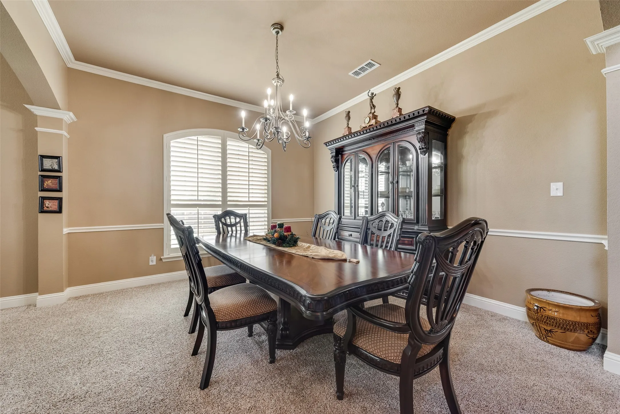 Dining area with ornate columns, crown molding, light carpet, and suspended lighting