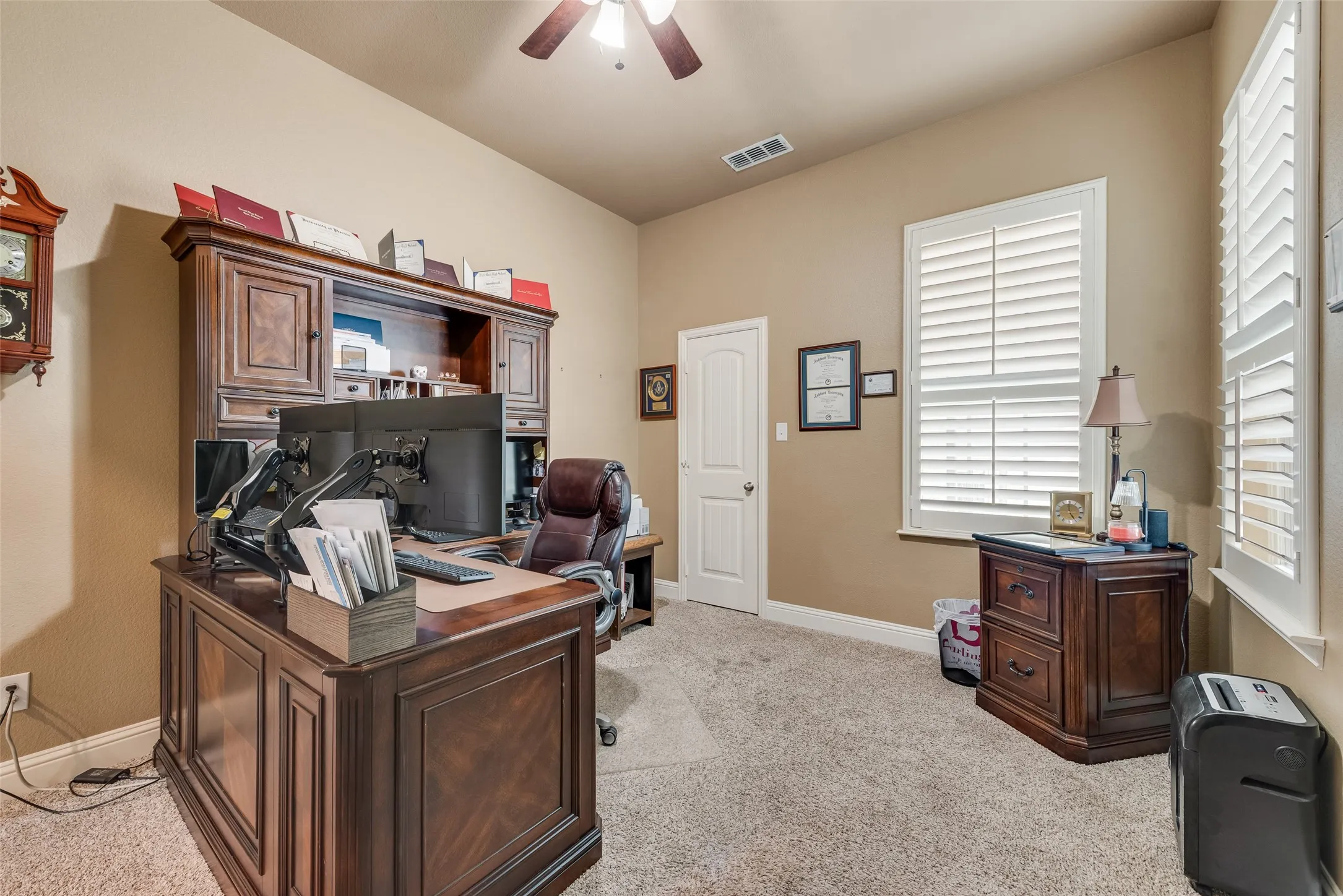 Office area featuring a ceiling fan and light carpet