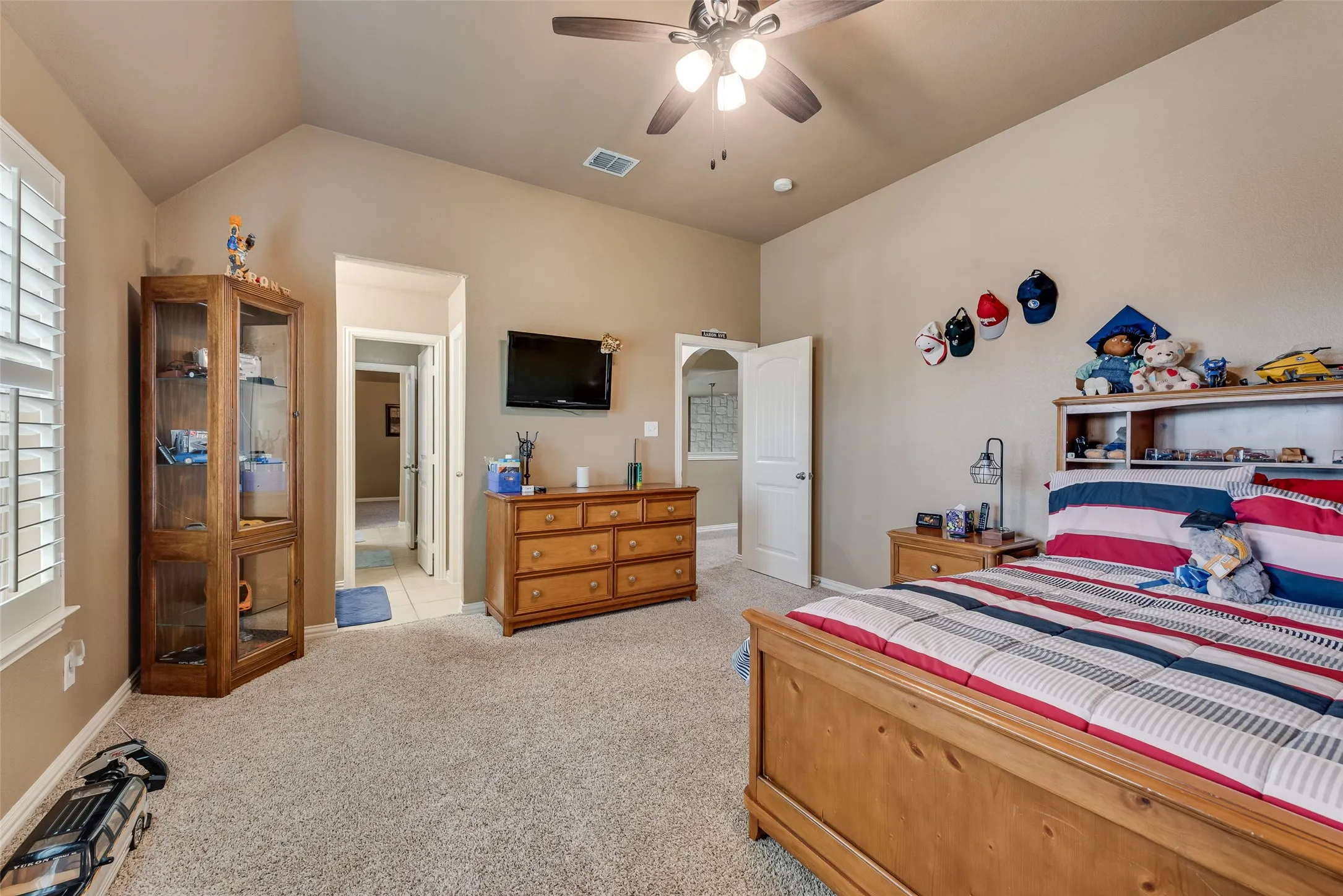 Bedroom with vaulted ceiling, a ceiling fan, and light carpet