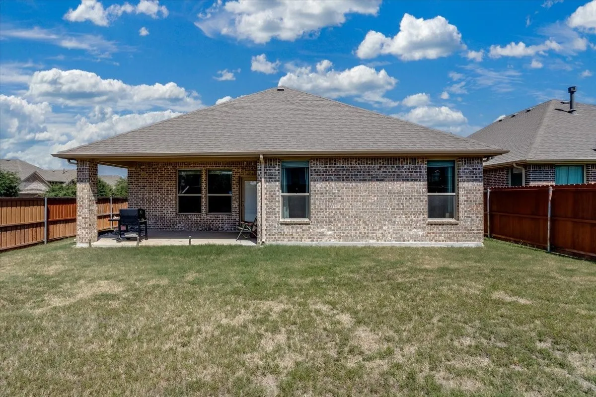 Brick exterior featuring a covered patio, multiple windows, and a shingled roof