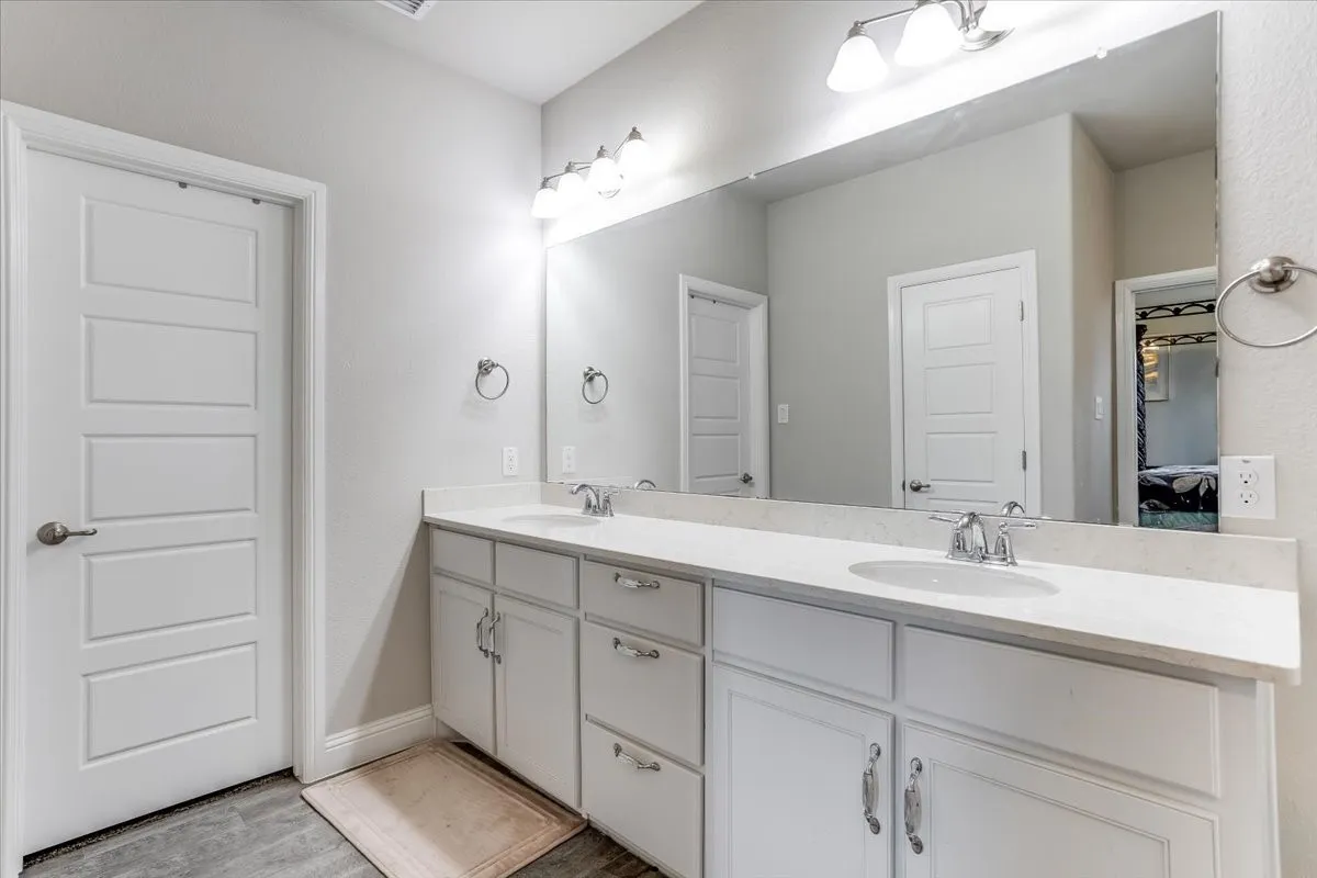 Dual vanity with white cabinetry, light-toned countertops, and chrome fixtures