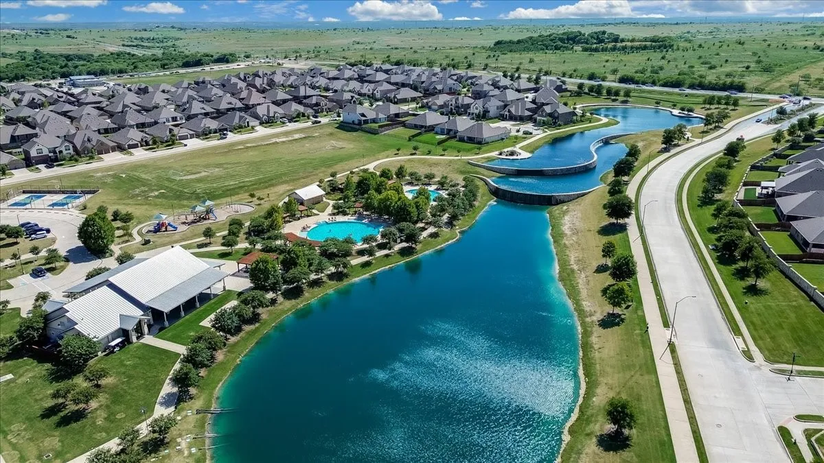 Community featuring multiple bodies of water, a large recreational building, two swimming pools, and a playground