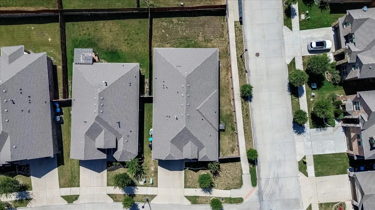 Neighborhood featuring a concrete street, sidewalks, and residential structures with gray shingle roofs