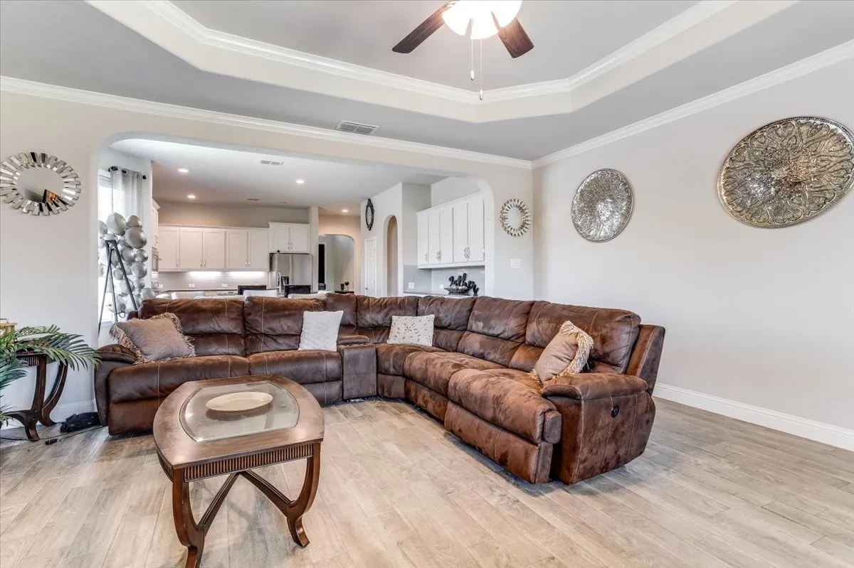 Tray ceiling with crown molding and ceiling fan, wood-finish flooring, and recessed lighting