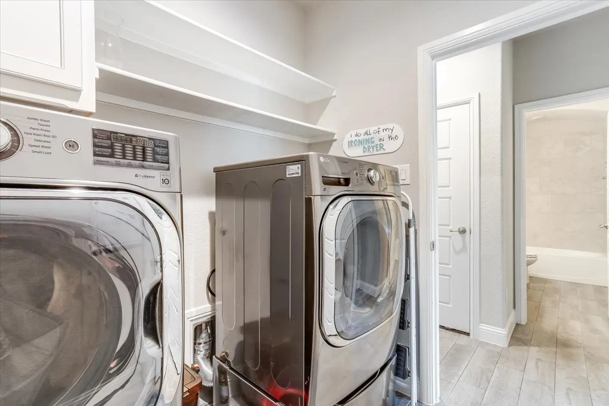 Laundry area featuring white cabinetry, built-in shelving, and wood-finish flooring