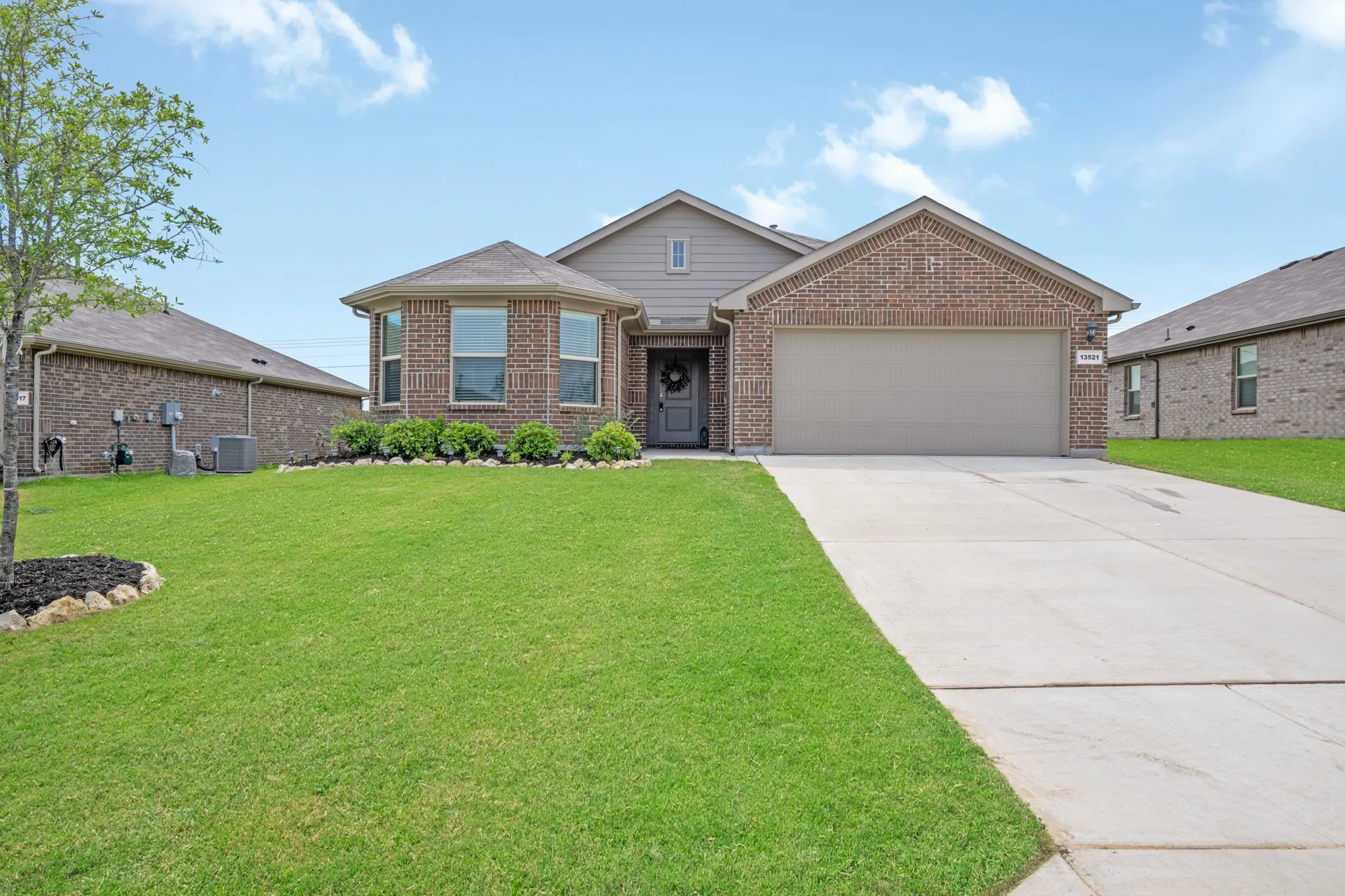 Single story home with an attached garage, driveway, a front lawn, and brick siding