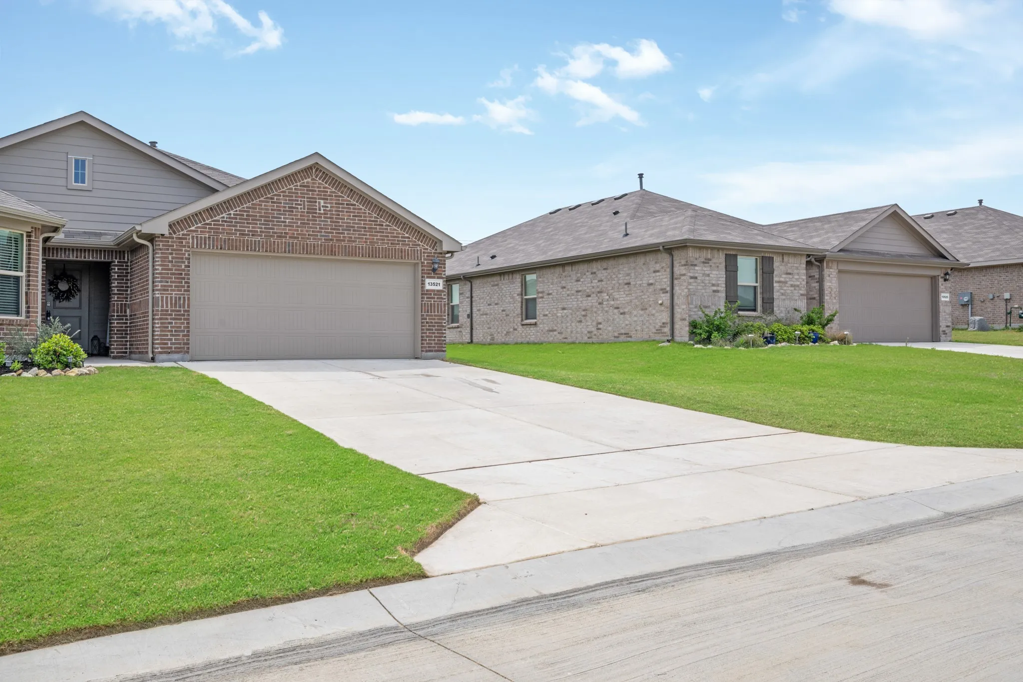 Single story home with a front yard, brick siding, a garage, and concrete driveway