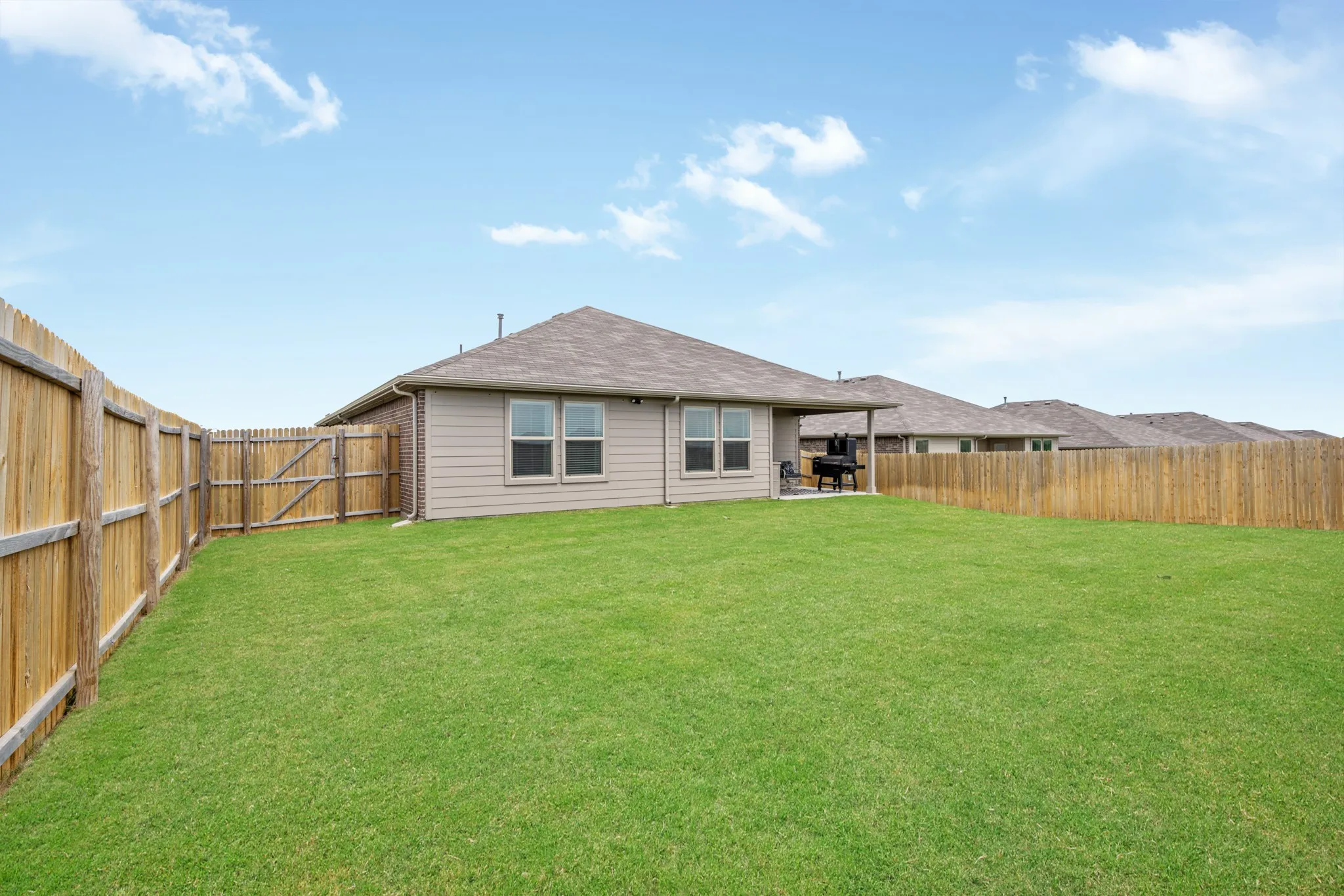 Rear view of property featuring a patio, a fenced backyard, and roof with shingles