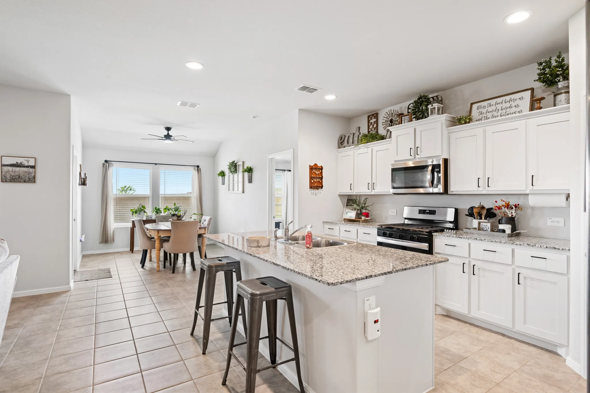 Kitchen with stainless steel appliances, white cabinets, a kitchen breakfast bar, recessed lighting, and light tile patterned floors