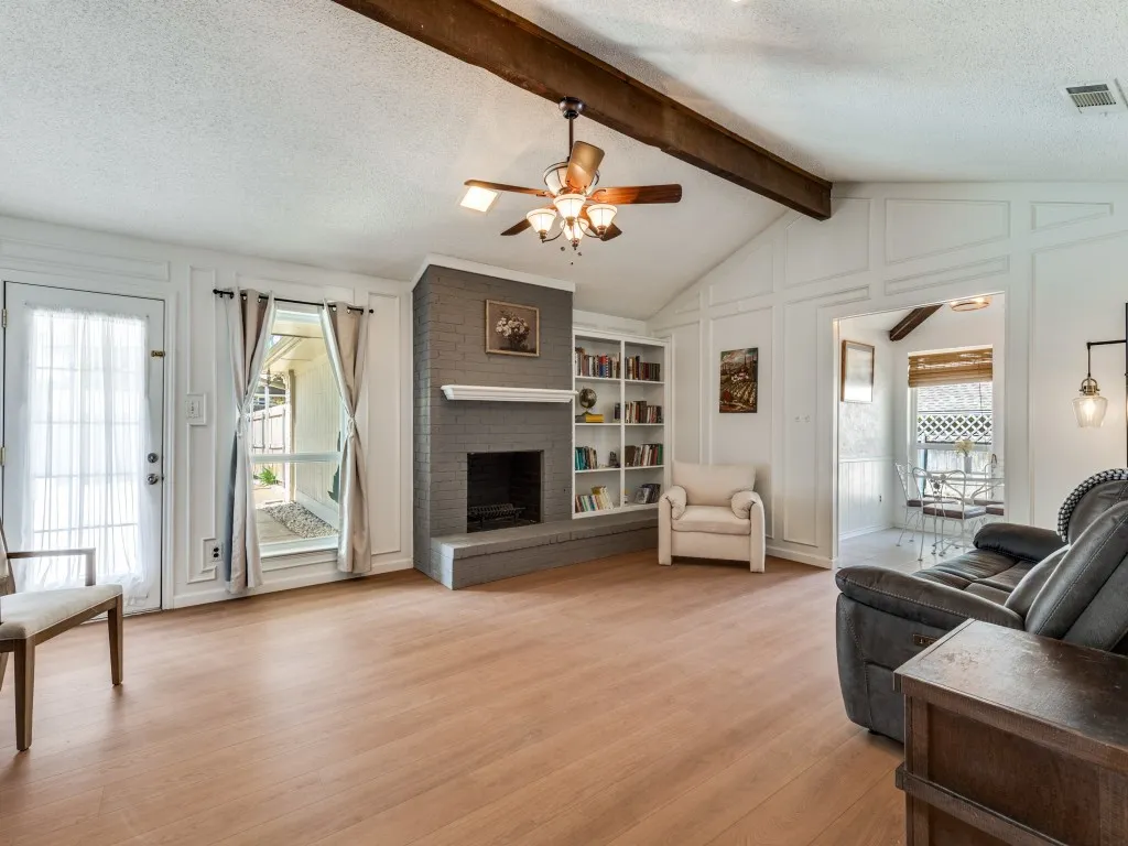 Living room features vaulted ceilings, a gas-start wood-burning brick fireplace, and built-in custom shelves.
